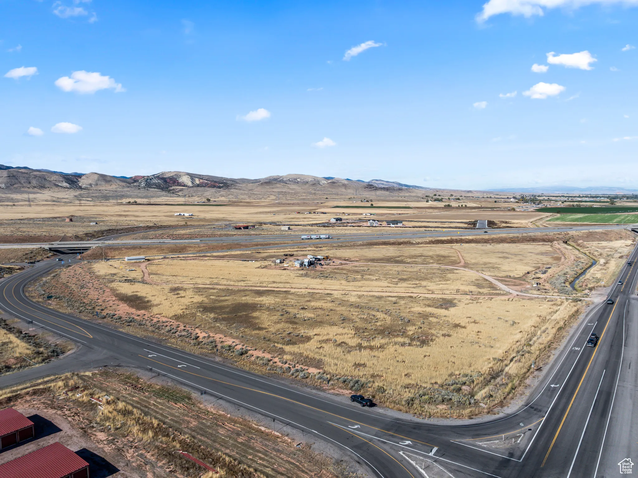 Aerial view of sparsely populated area with a mountain backdrop and a major roadway