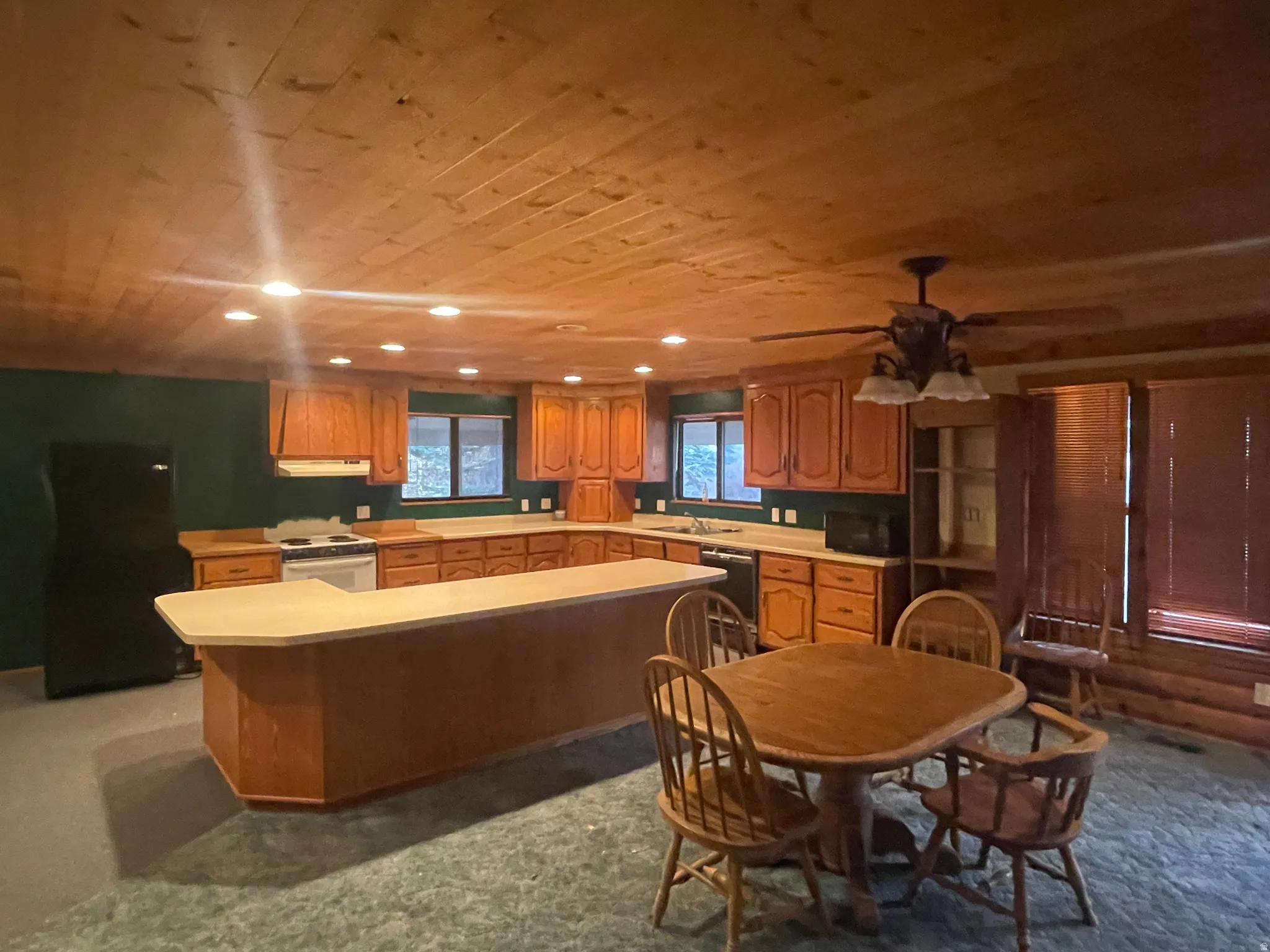 Kitchen featuring wood ceiling, light countertops, brown cabinets, a kitchen island, and black appliances