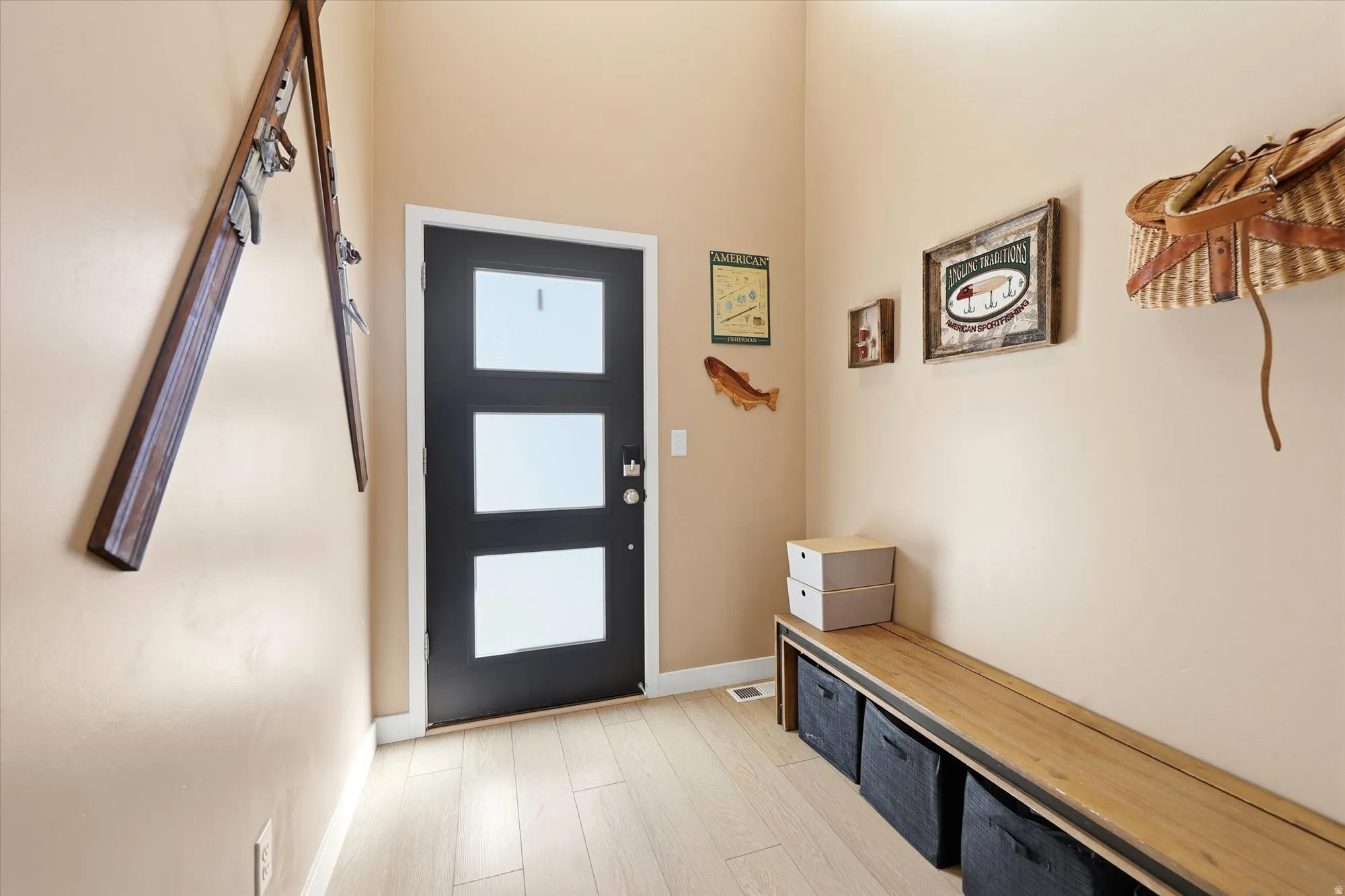 Entryway featuring a black door with three rectangular frosted glass panels, wood-finish flooring, and light beige wall paint