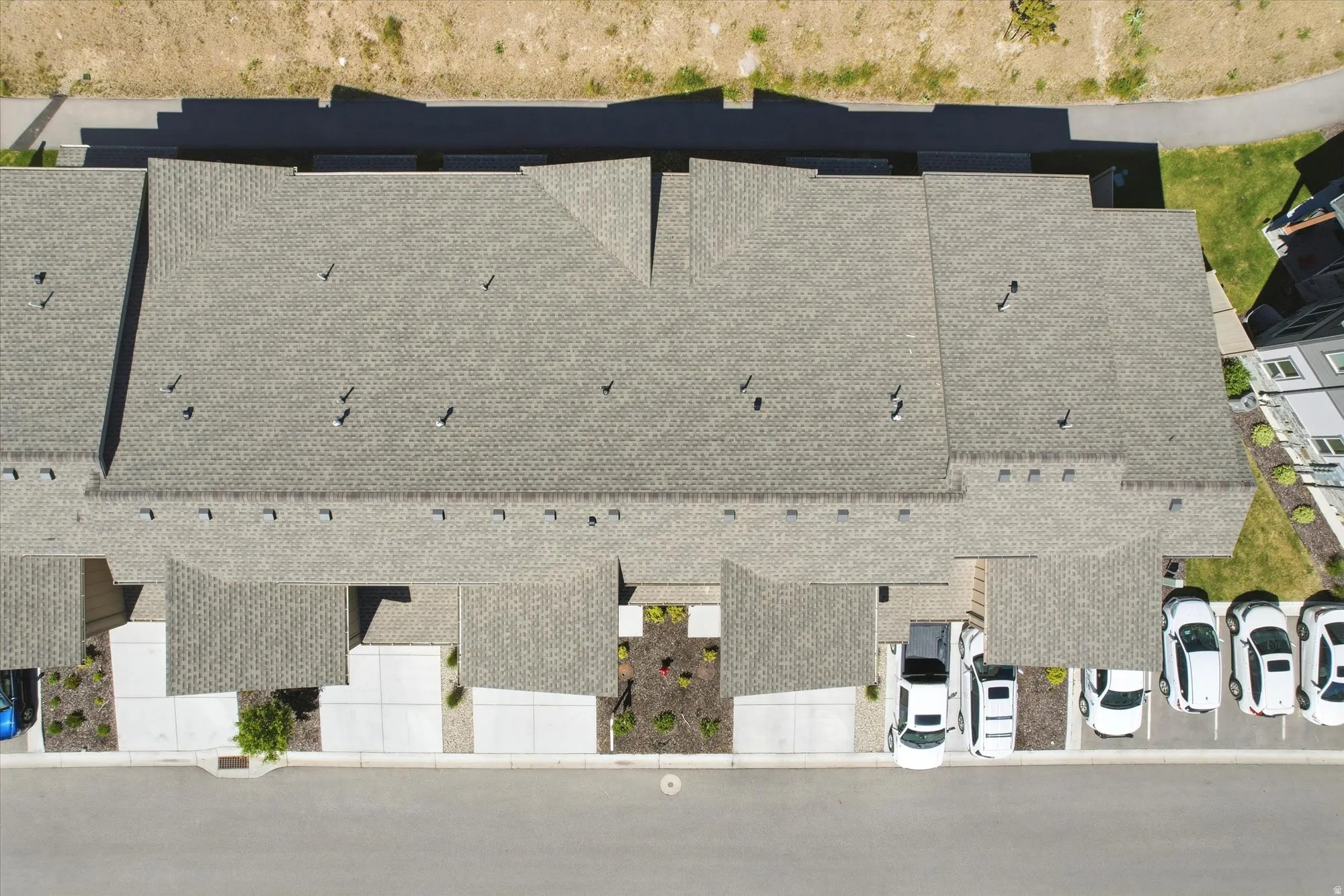 Townhome community featuring pitched composition shingle roofs, individual concrete driveways, and designated parking spaces