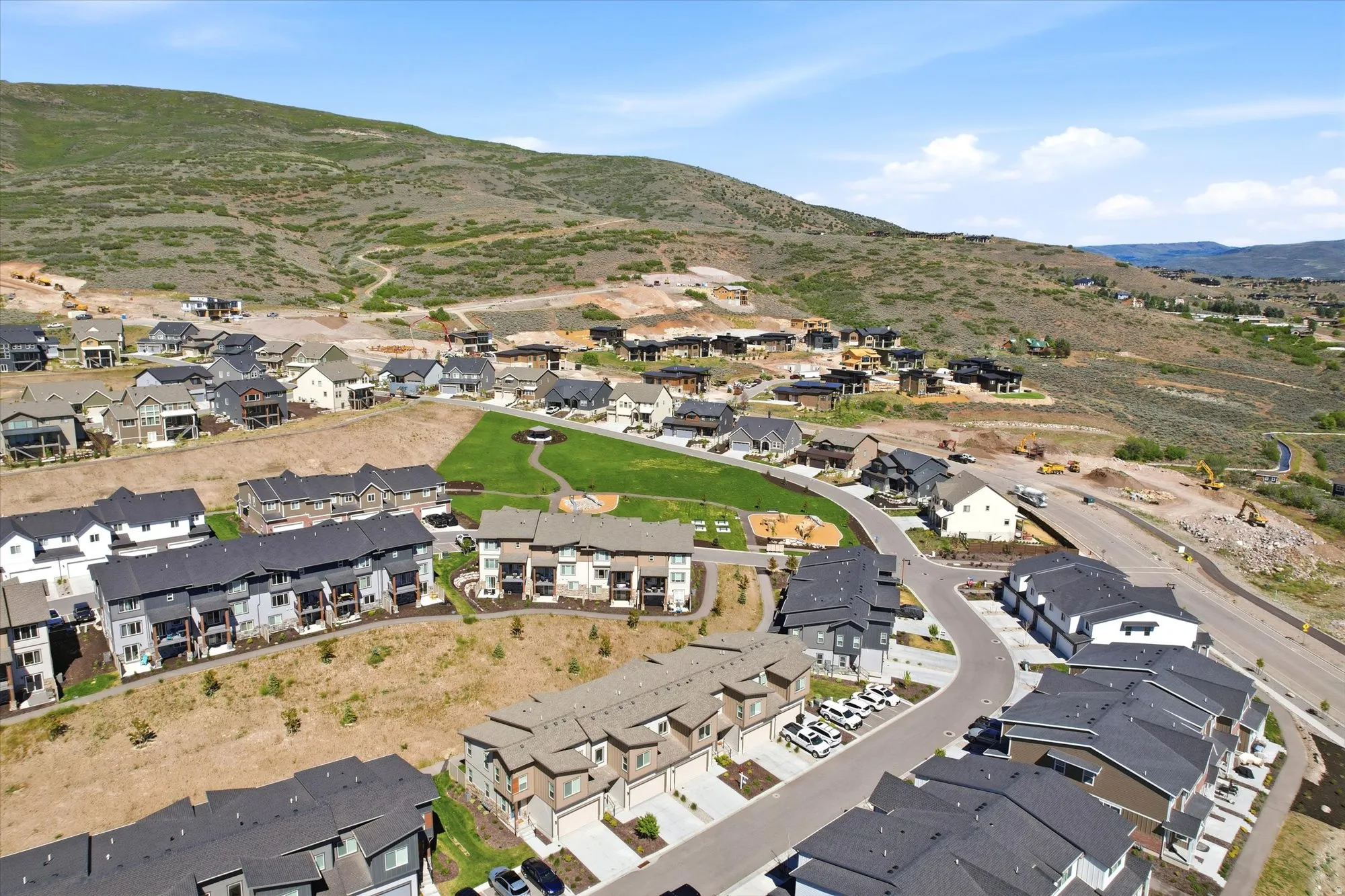 Residential community featuring a mix of single-family homes and townhomes, surrounded by natural hillside terrain