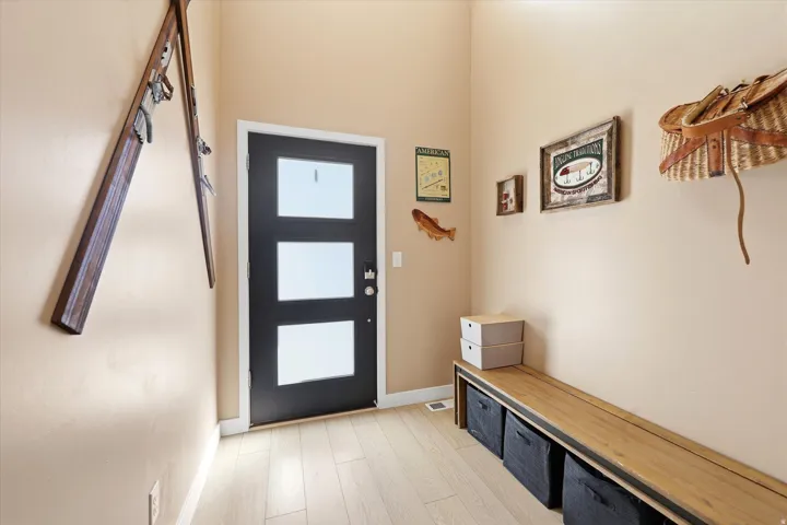 Entryway featuring a black door with three rectangular frosted glass panels, wood-finish flooring, and light beige wall paint
