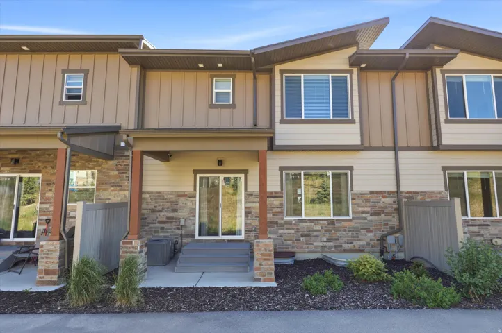 Exterior featuring a stone and siding facade, multiple large windows, covered patios, and a contemporary roofline