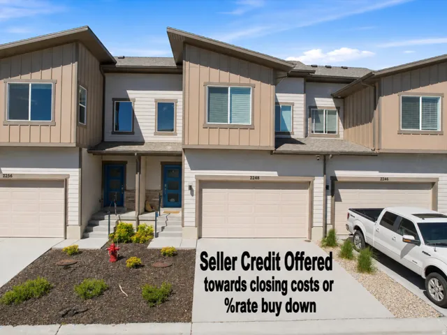 Contemporary multi-story townhome with tan siding and dark blue entry doors