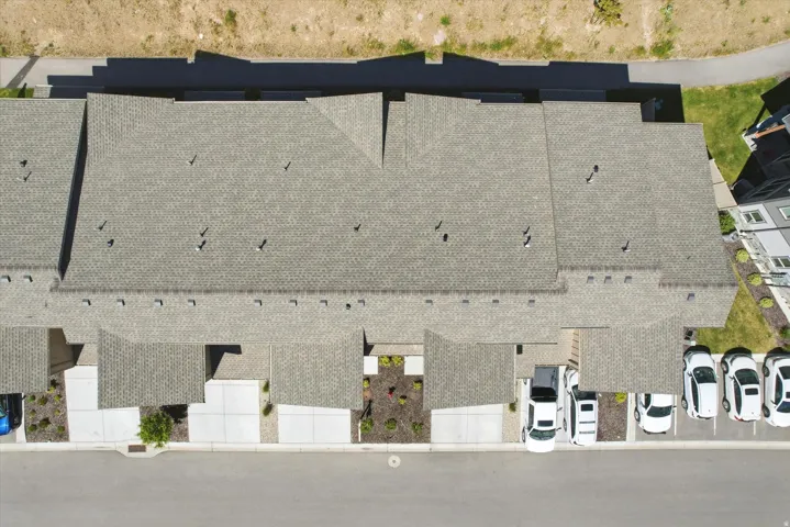 Townhome community featuring pitched composition shingle roofs, individual concrete driveways, and designated parking spaces