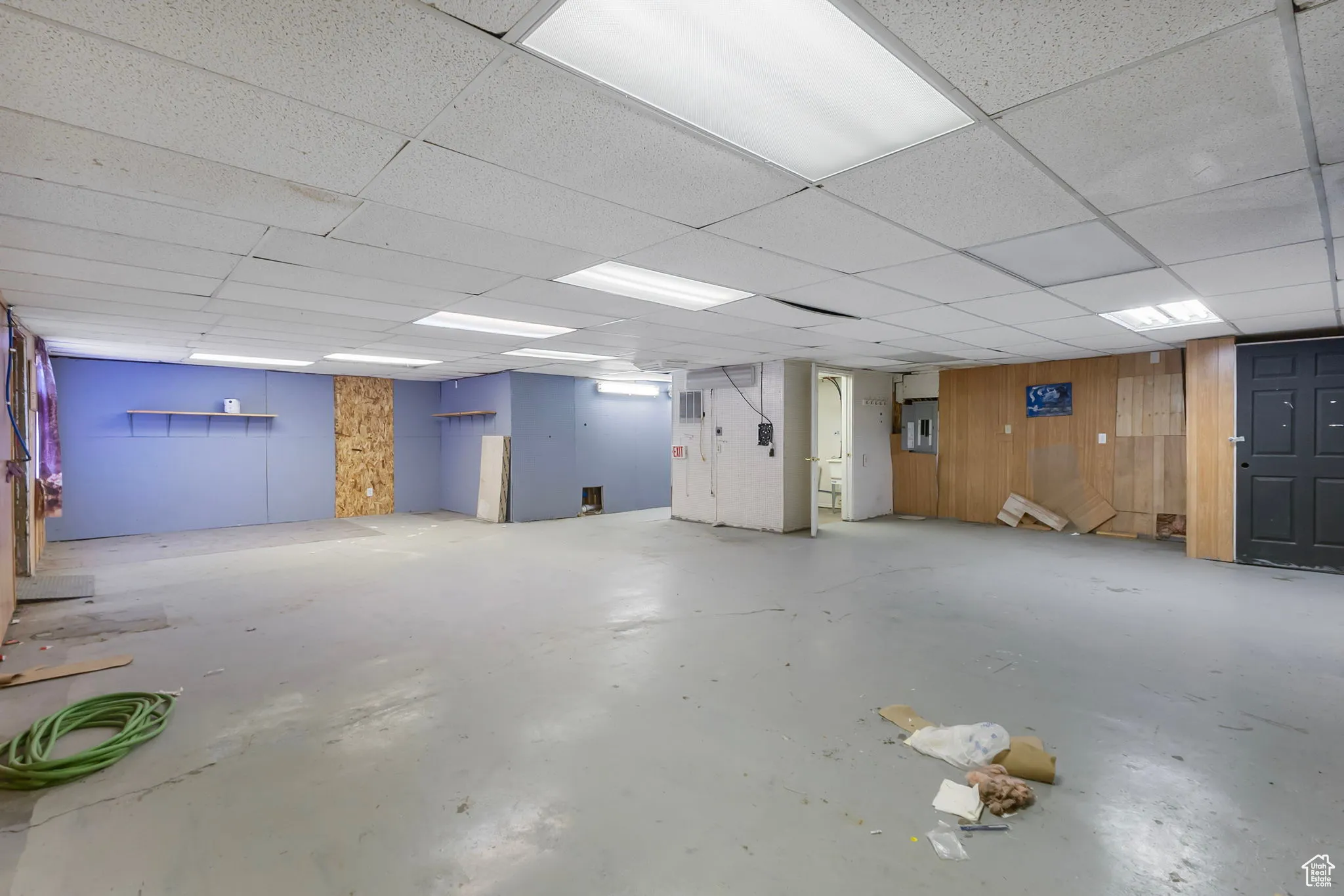 Below grade area featuring wooden walls and a drop ceiling