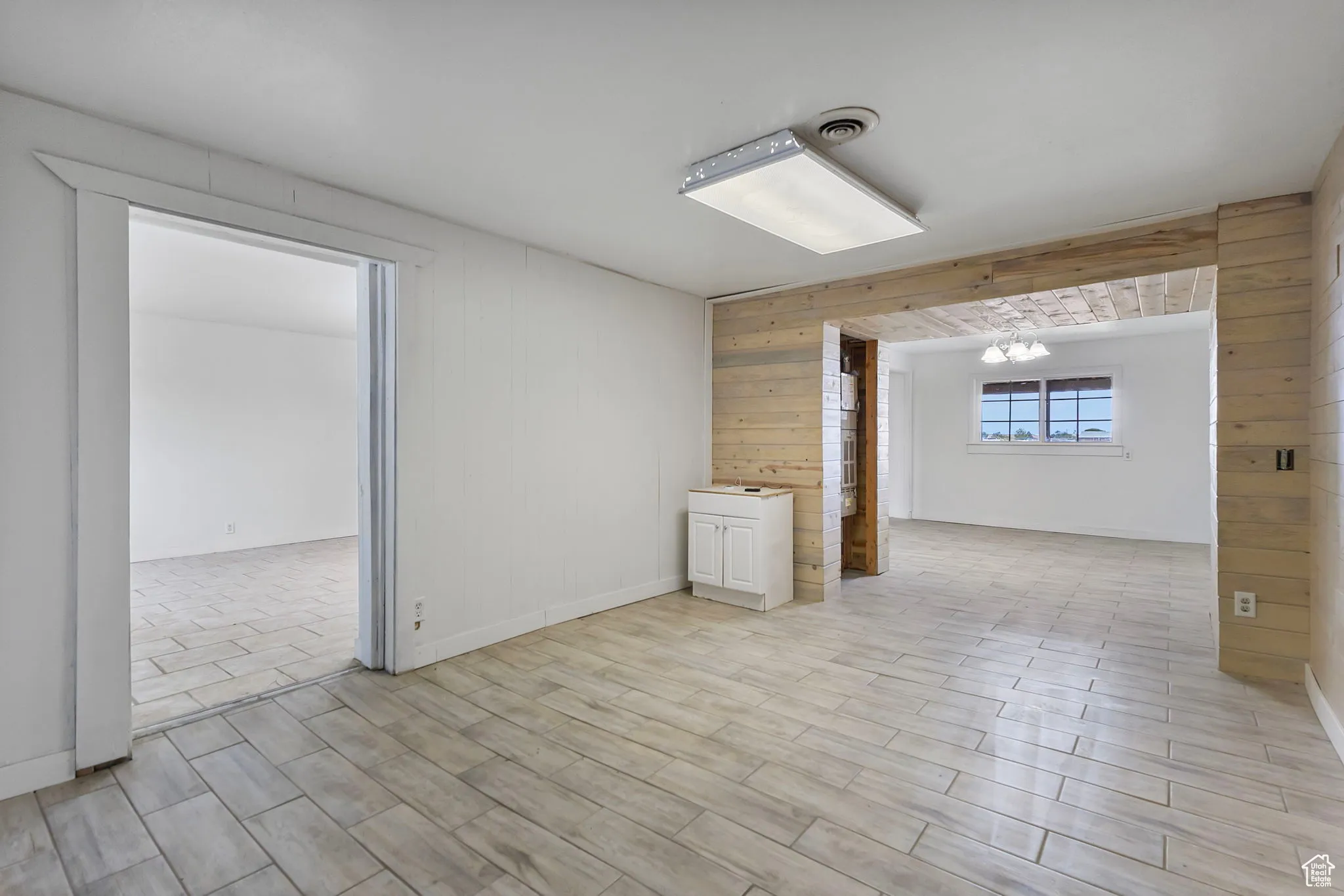 Spare room with wooden walls, wood finish floors, and a chandelier