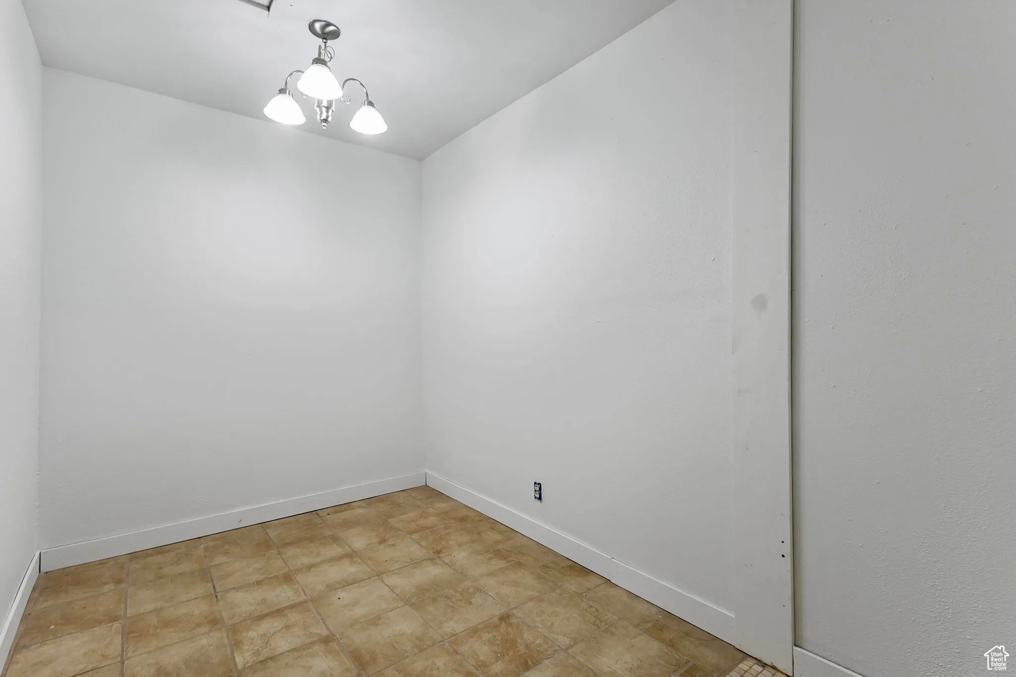 Spare room with baseboards and a chandelier