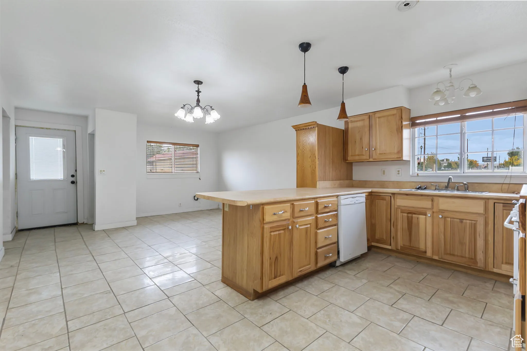 Kitchen with a chandelier, light countertops, a peninsula, and white appliances