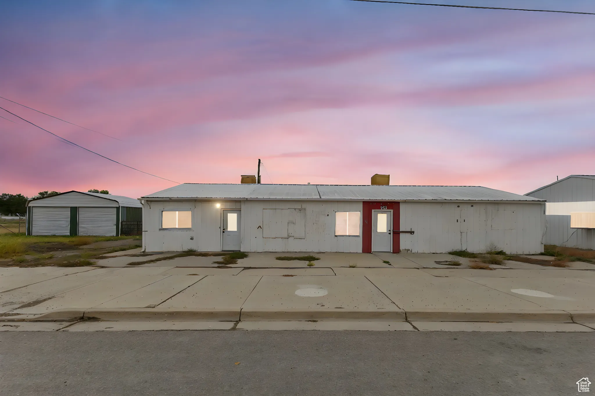 View of front of property with a metal roof, a detached garage, an outbuilding, and a chimney