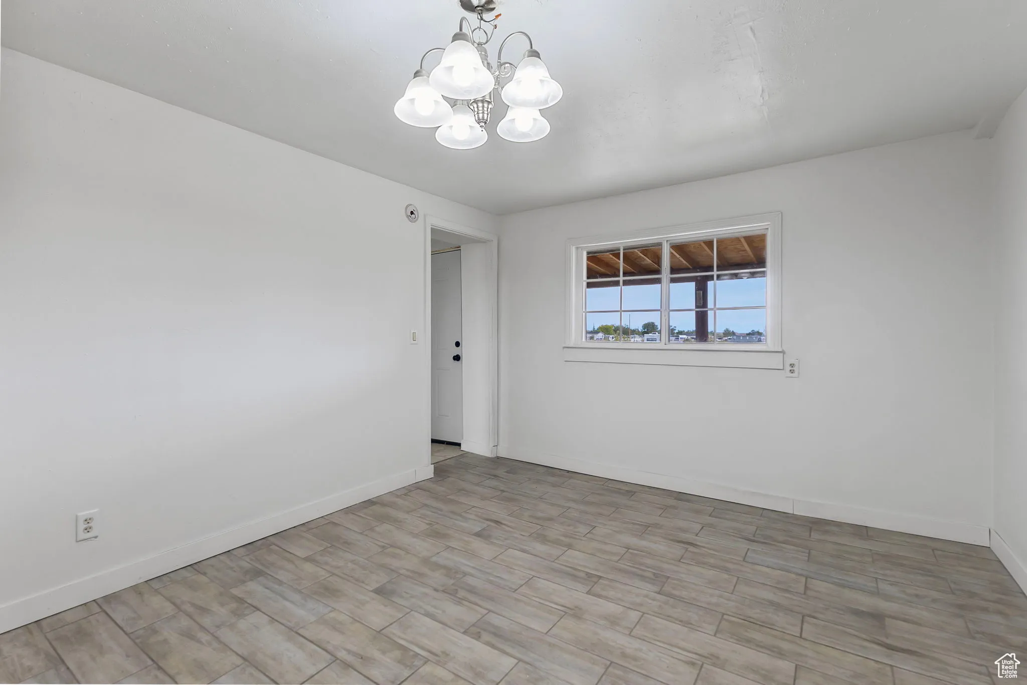 Spare room featuring wood tiled floors and a chandelier