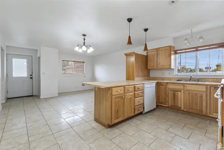 Kitchen with a chandelier, light countertops, a peninsula, and white appliances