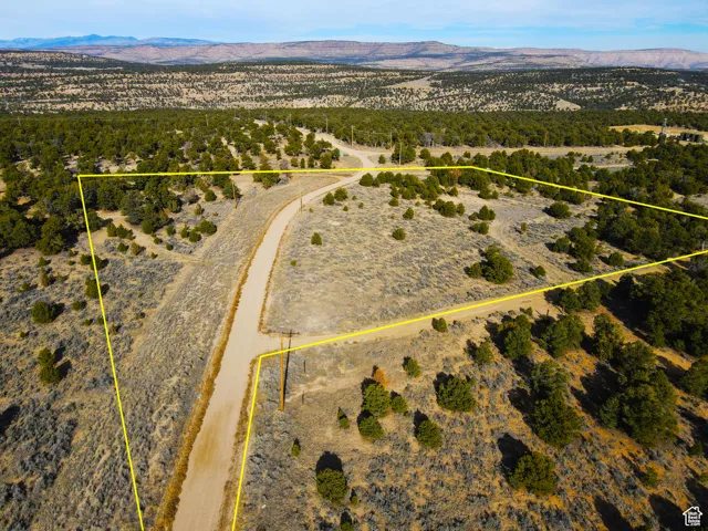 Aerial view of sparsely populated area featuring a mountain backdrop and property parcel outlined