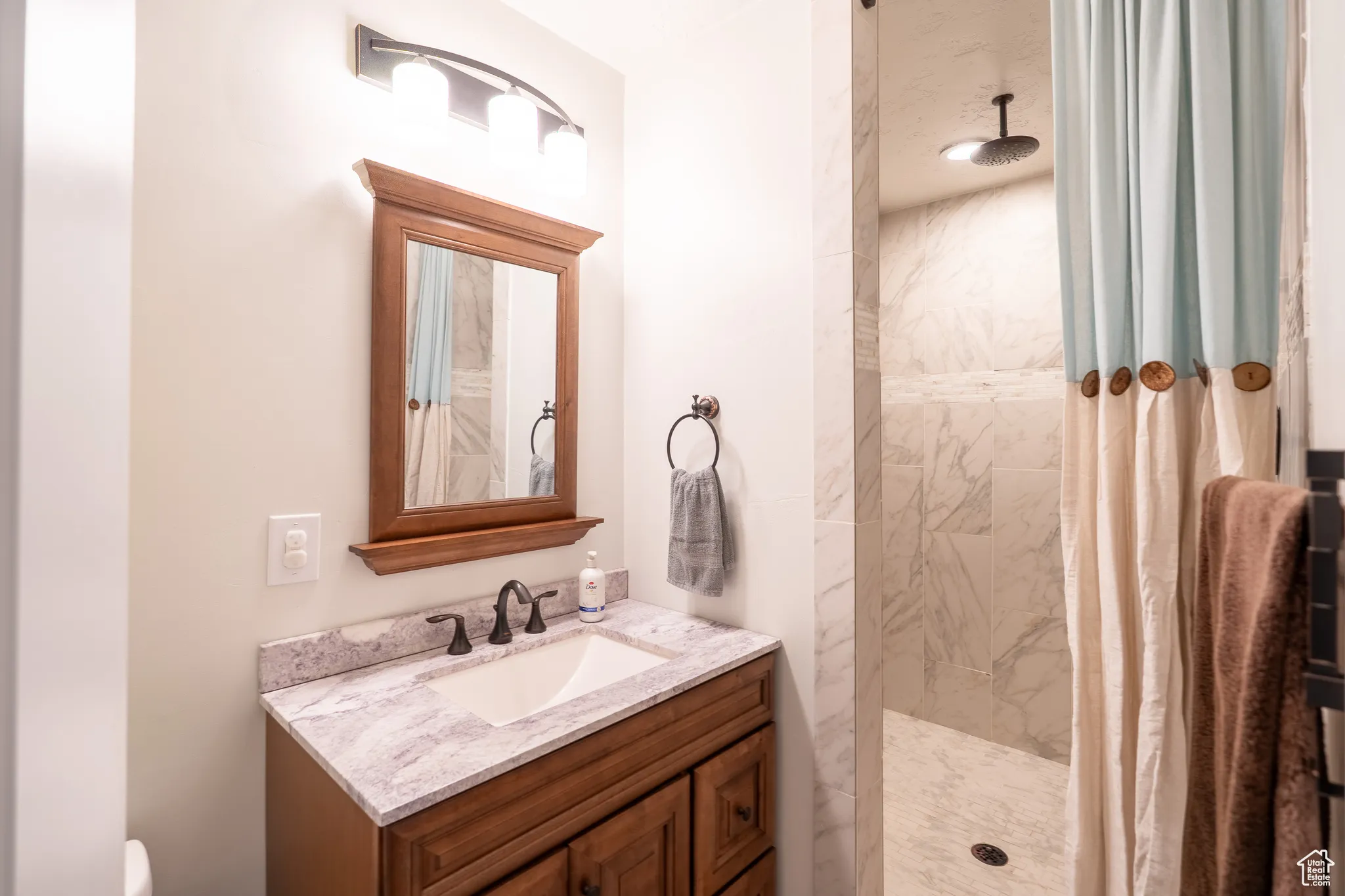 Bathroom featuring a marble finish shower and vanity
