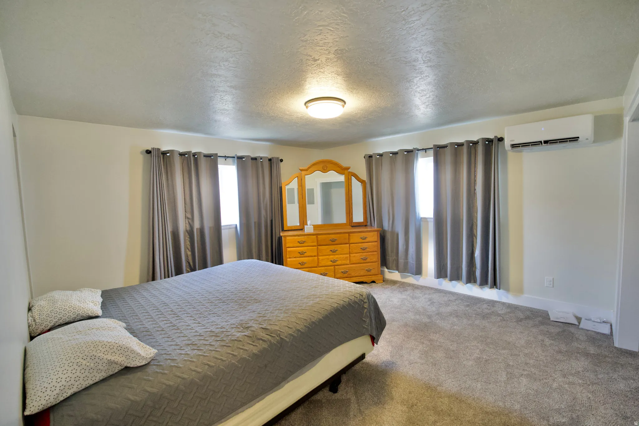 Recessed lighting, carpeted flooring, window treatments, and a wall-mounted climate control unit