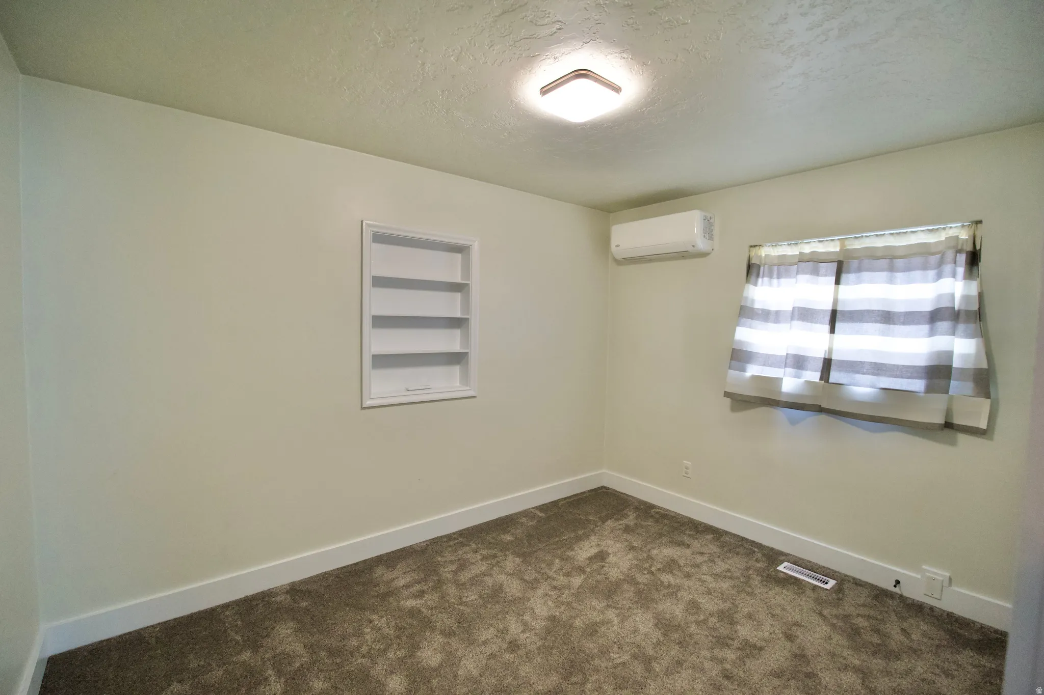 Recessed wall shelving, wall-mounted air conditioning unit, window, and flush-mount ceiling light