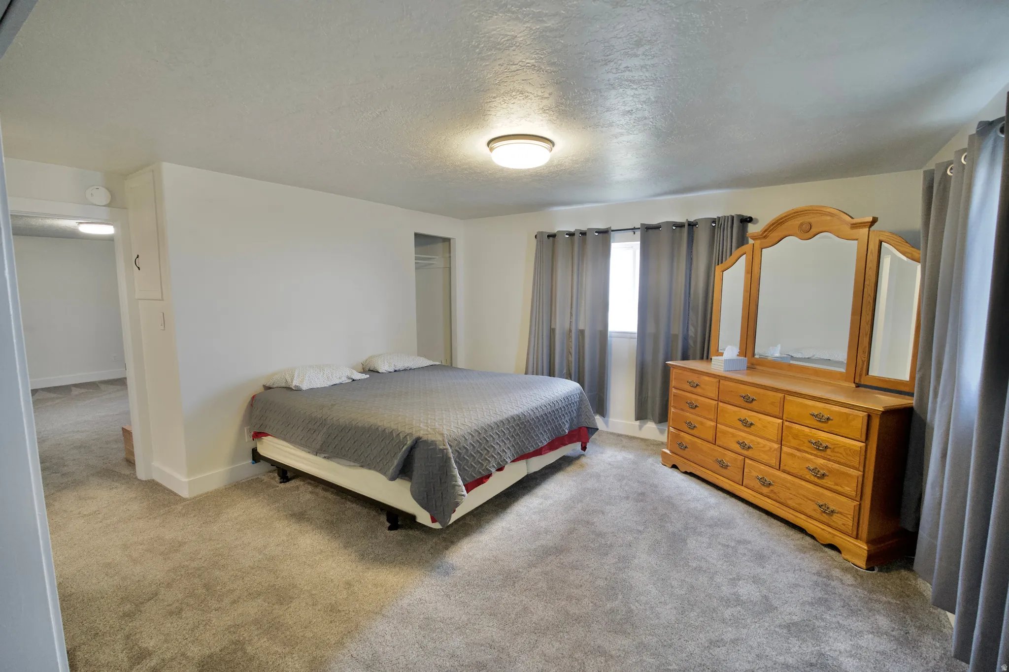 Wall-to-wall carpeting throughout, a window with drapery, and a flush-mount ceiling light fixture