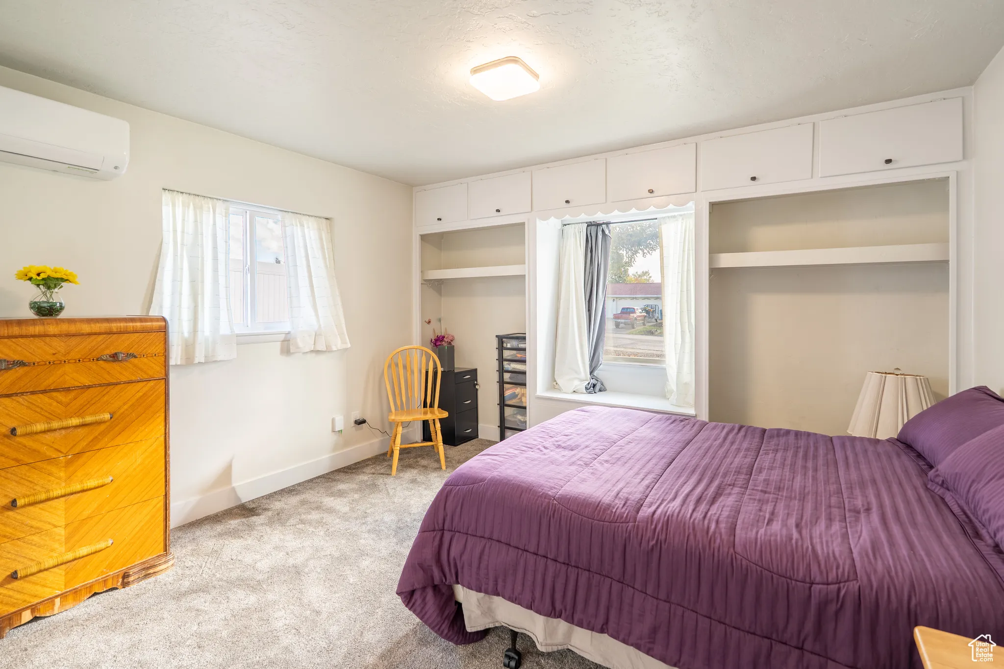 Bedroom featuring carpet flooring, a wall mounted air conditioner, and a textured ceiling