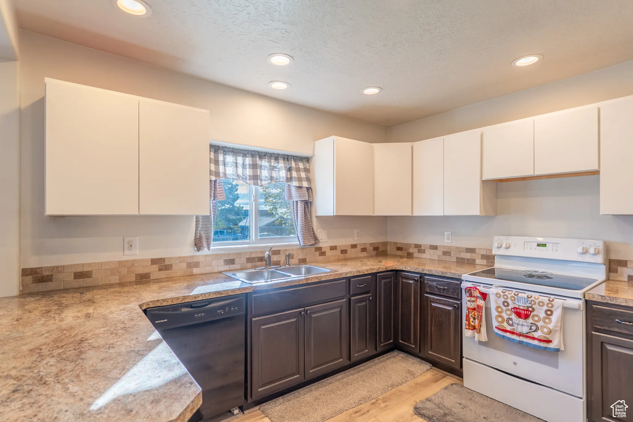 Kitchen with white electric stove, black dishwasher, recessed lighting, white cabinets, and light wood finished floors