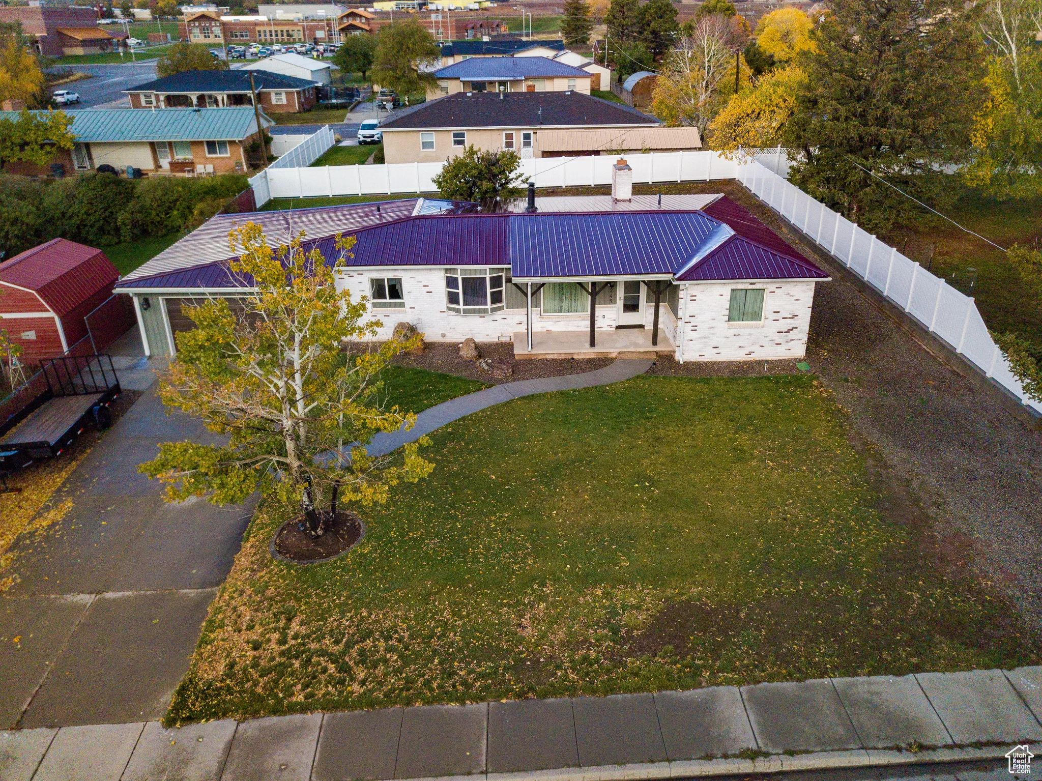 View of front of home with a metal roof, driveway, a fenced backyard, and a residential view