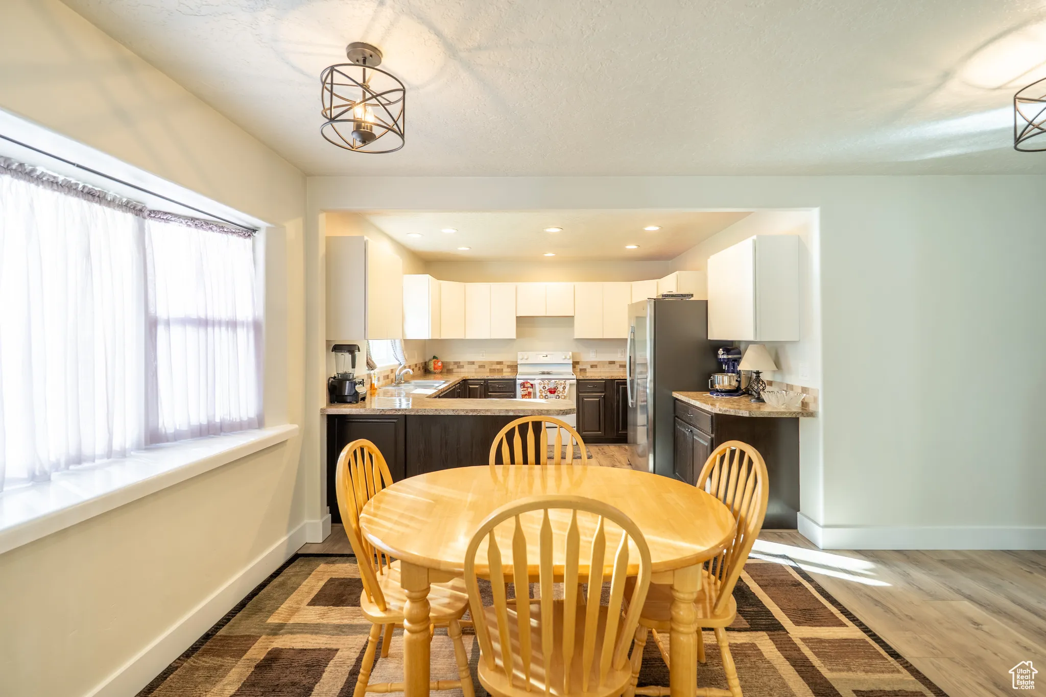 Dining room with light wood finished floors, recessed lighting, and a textured ceiling
