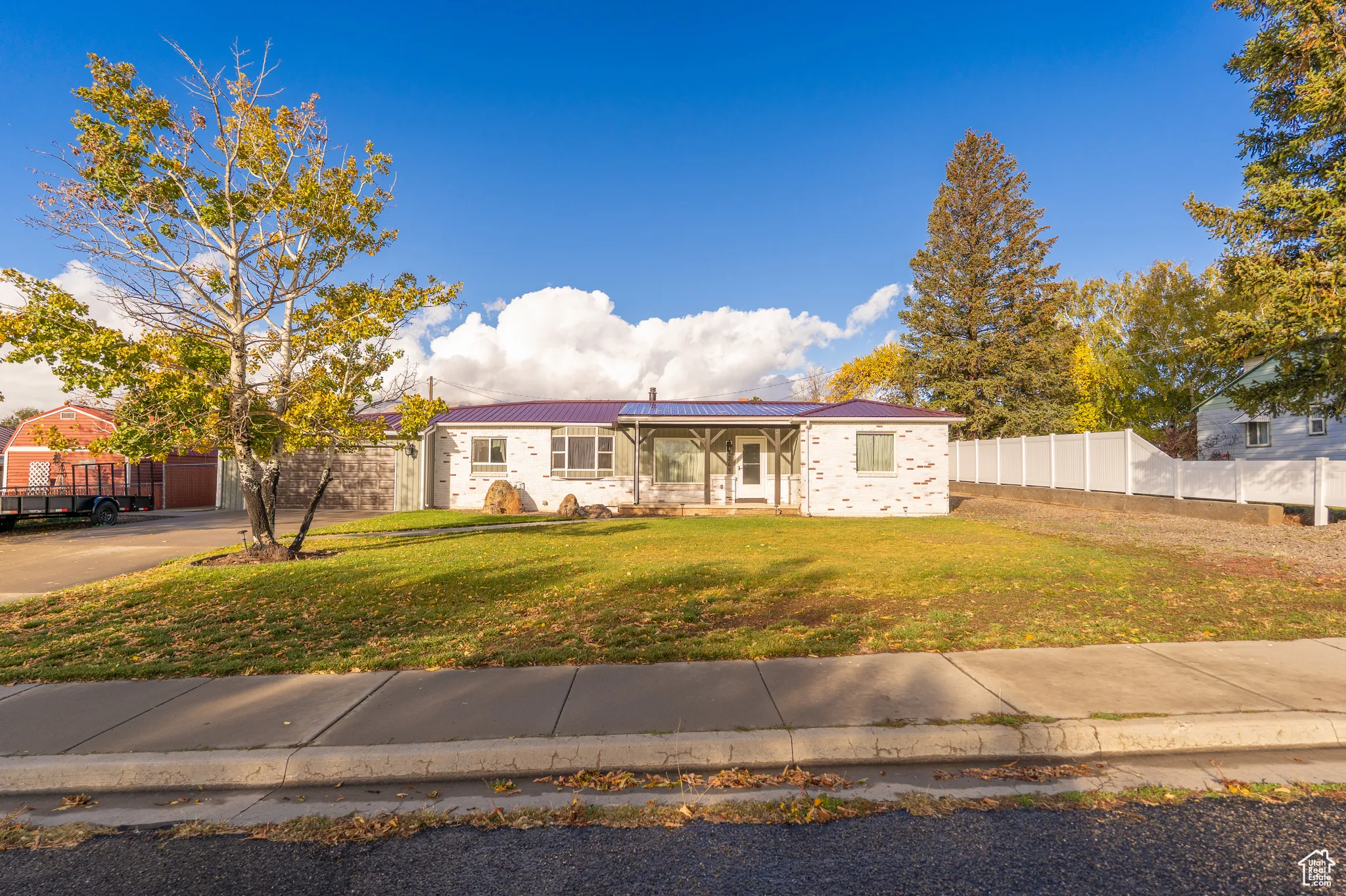 Ranch-style house with a metal roof, roof mounted solar panels, and concrete driveway