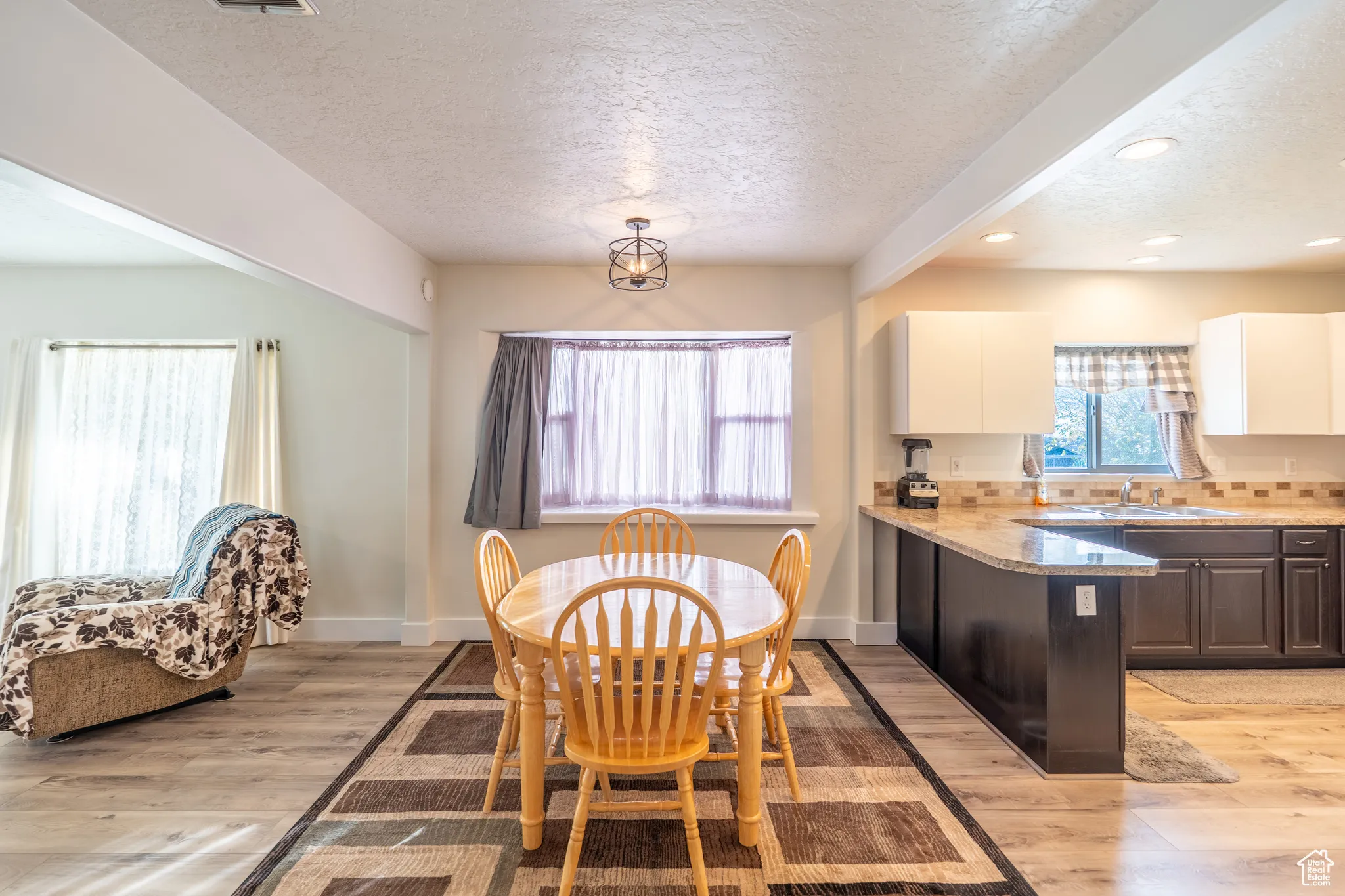 Dining area with a textured ceiling, beamed ceiling, light wood-type flooring, and recessed lighting