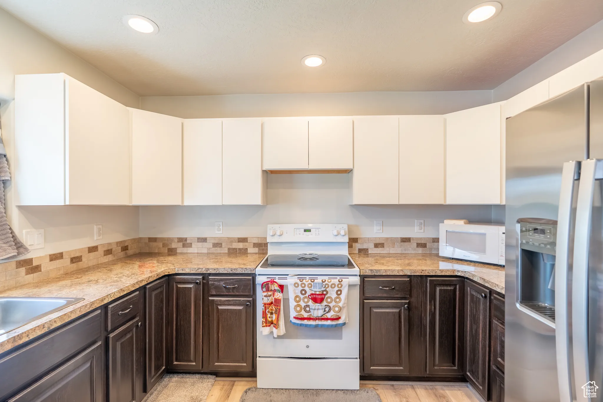 Kitchen featuring white appliances, dark brown cabinetry, white cabinetry, recessed lighting, and light wood-type flooring