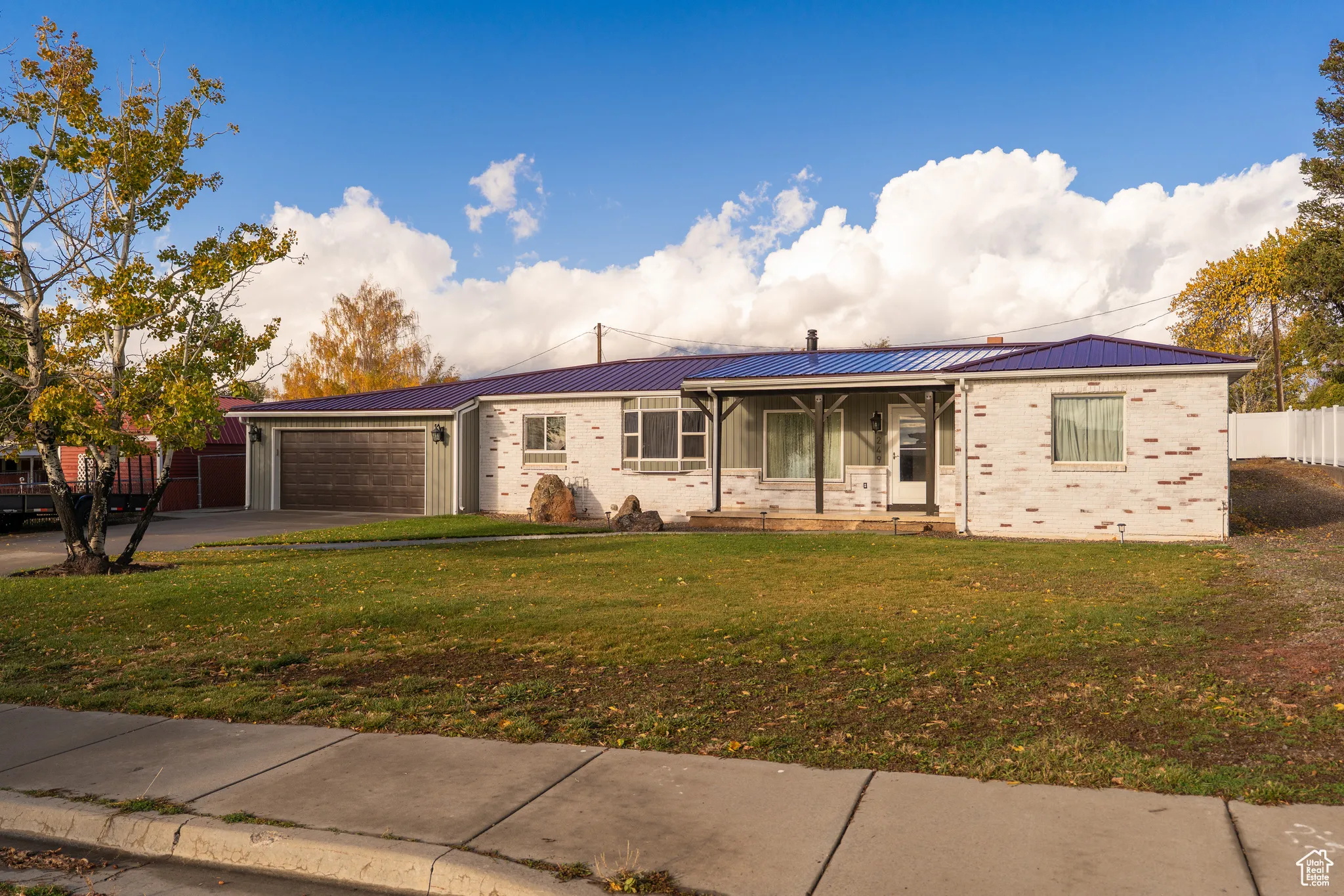 Ranch-style house featuring brick siding, covered porch, driveway, and a garage