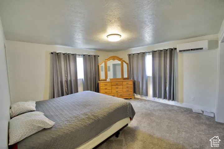 Recessed lighting, carpeted flooring, window treatments, and a wall-mounted climate control unit