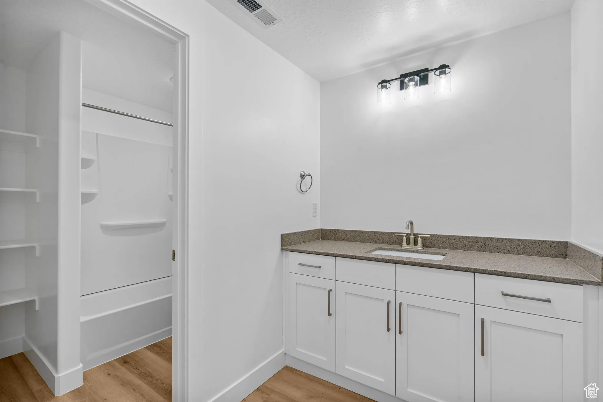 Bathroom with vanity, light wood-style flooring, a textured ceiling, and washtub / shower combination