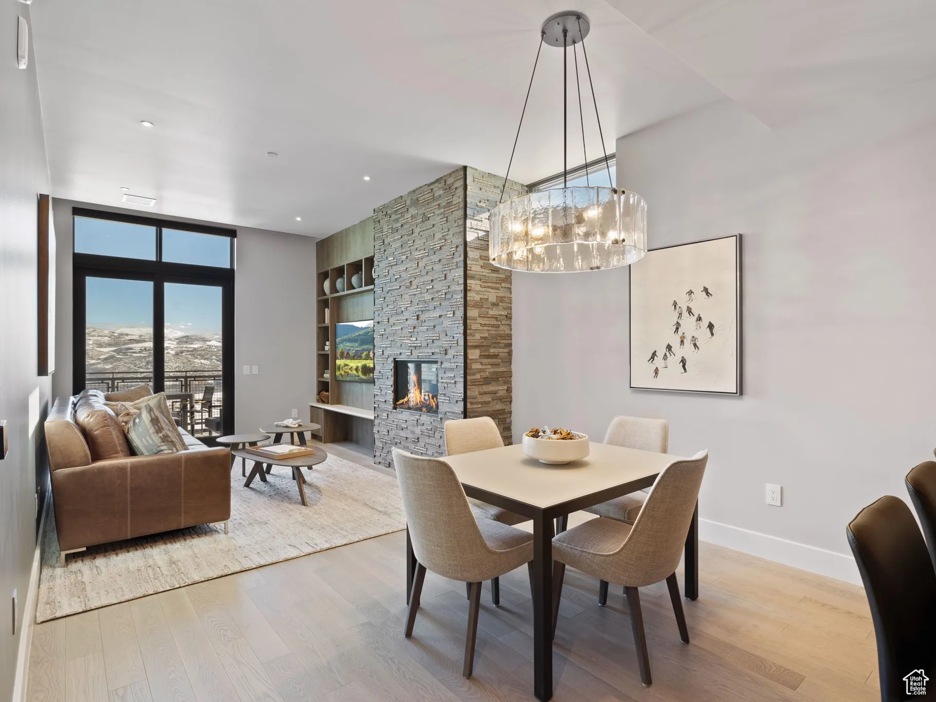 Dining area with light wood finished floors, a stone fireplace, built in features, and a chandelier