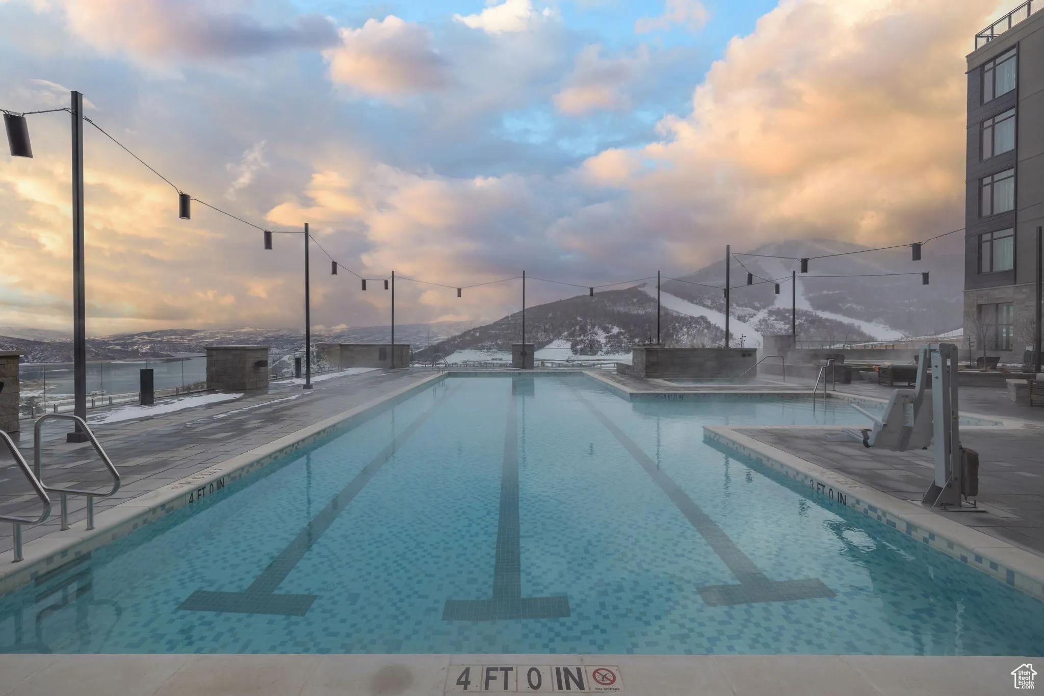 Pool at dusk with a community pool, a mountain view, and a patio area