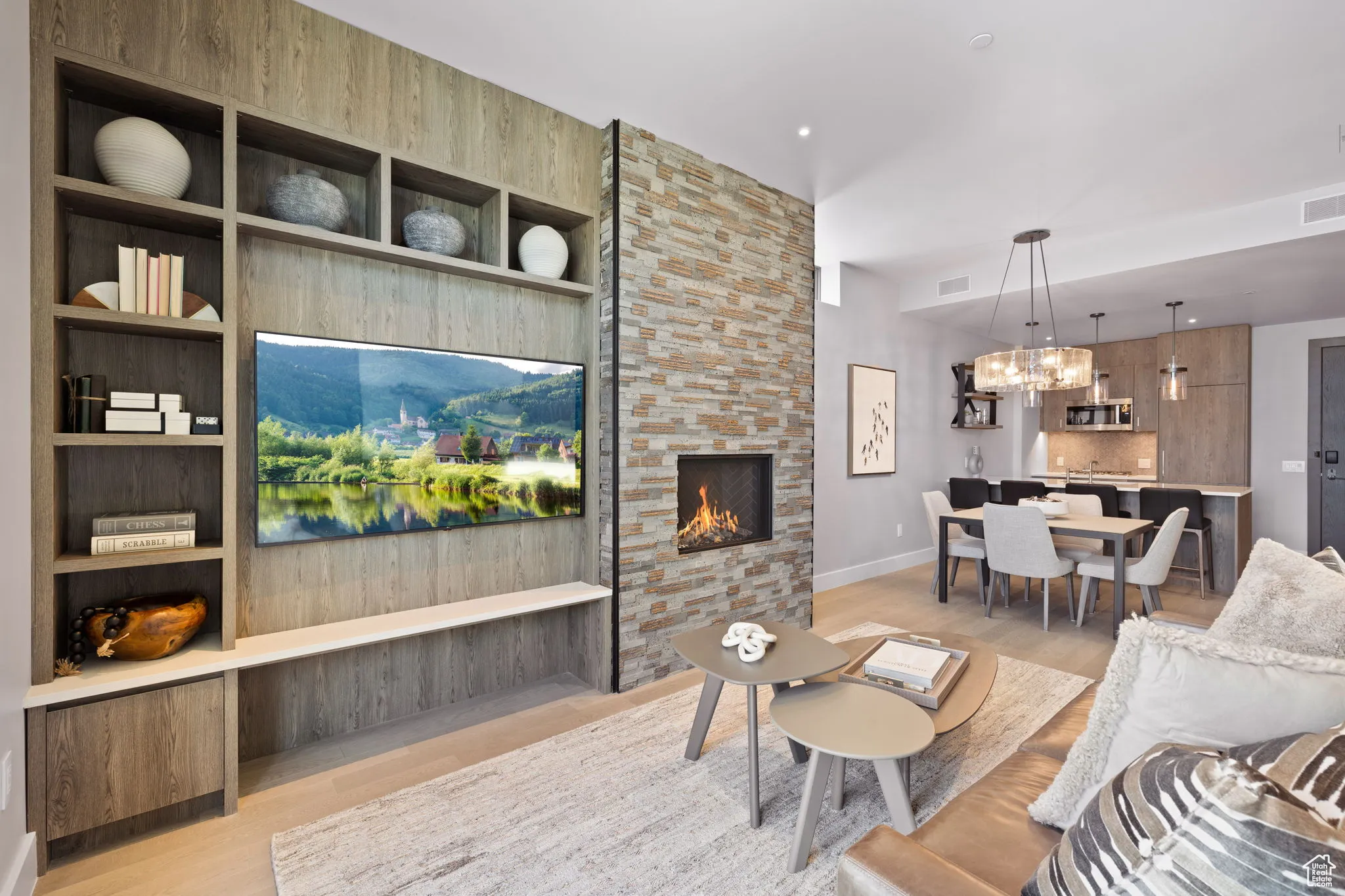 Living area with wood-floors, built in features, and a stone fireplace