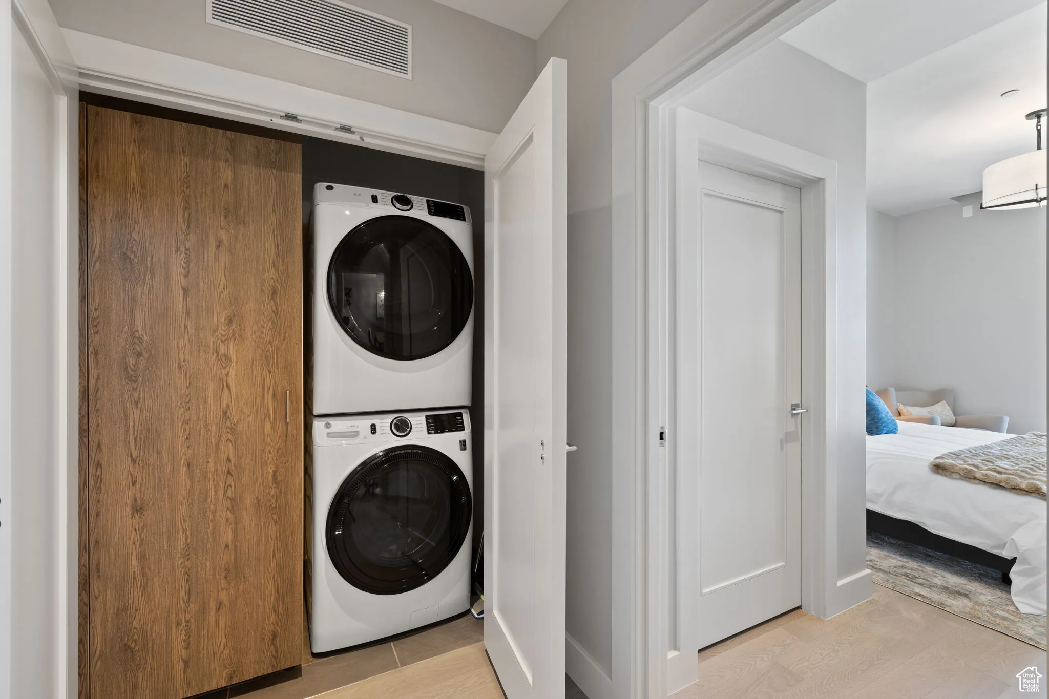 Laundry room featuring stacked full size washing machine and dryer and storage closet