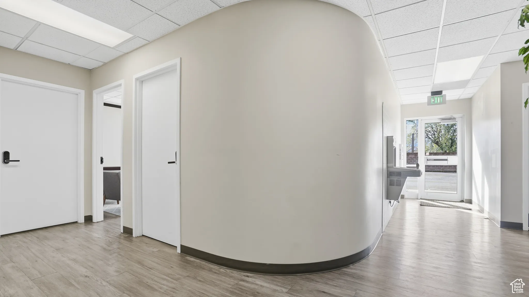 Corridor with a paneled ceiling and light wood-style floors
