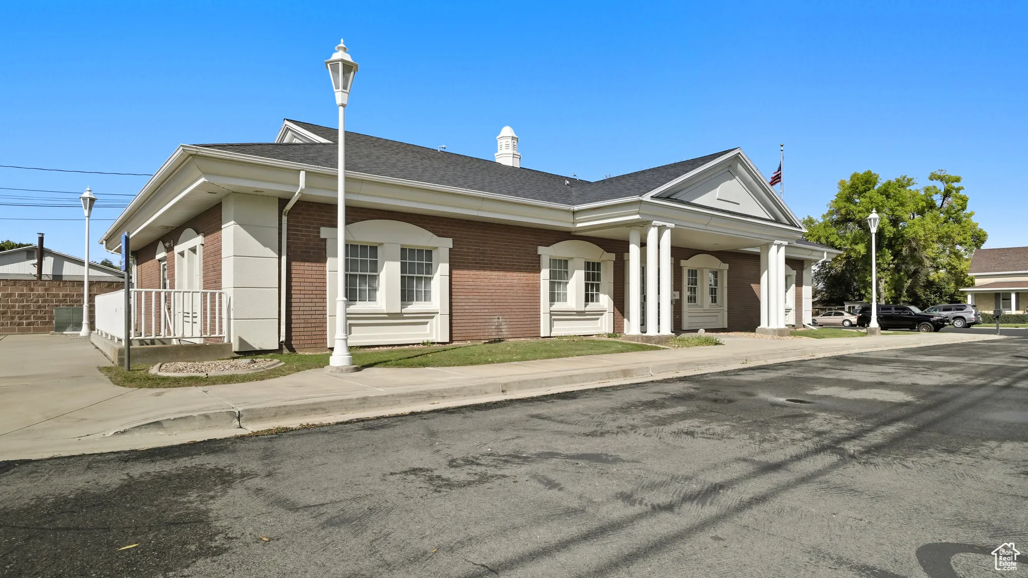 View of front facade with brick siding, roof with shingles, and a chimney