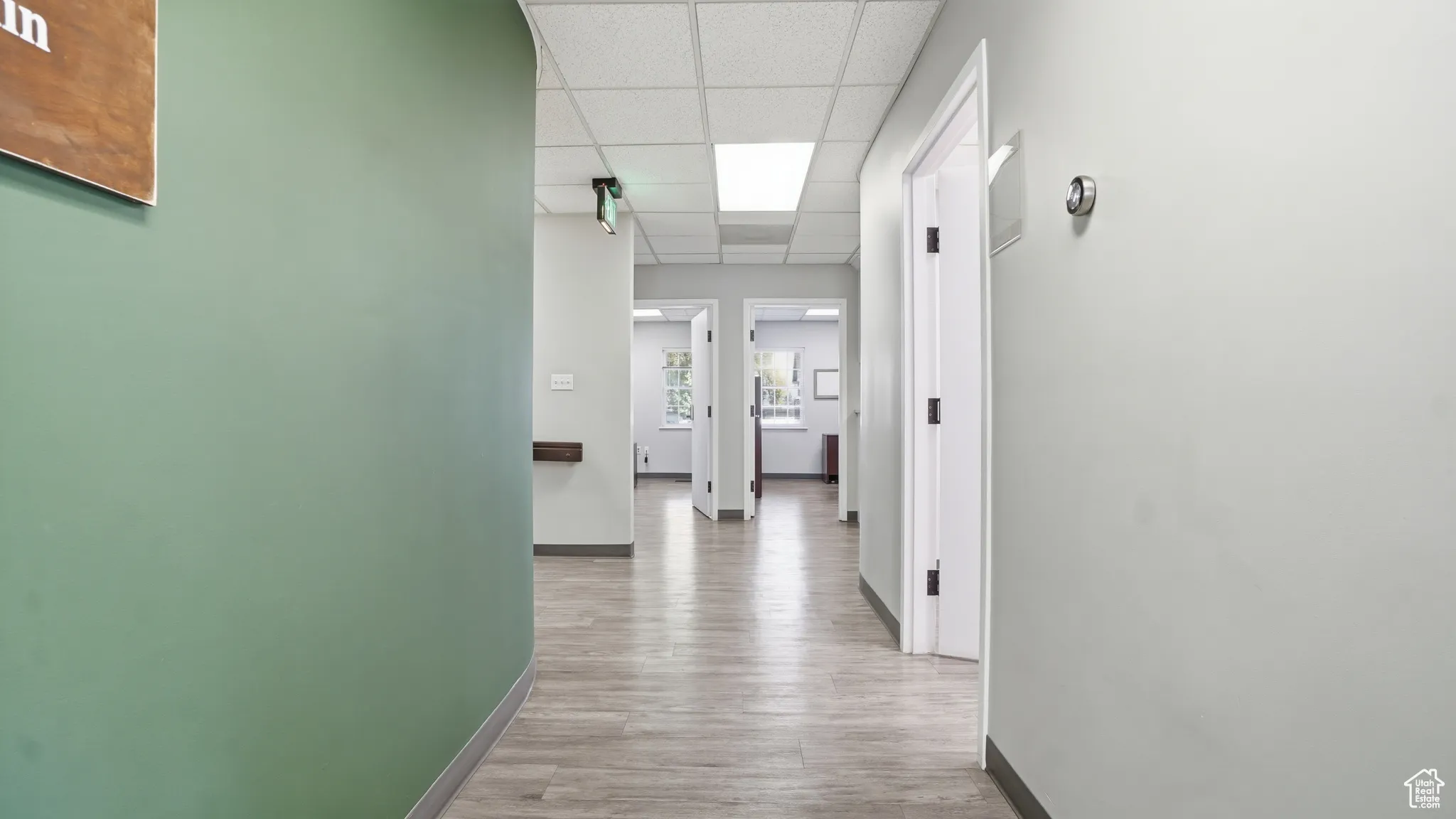 Hallway with a paneled ceiling and light wood-style floors