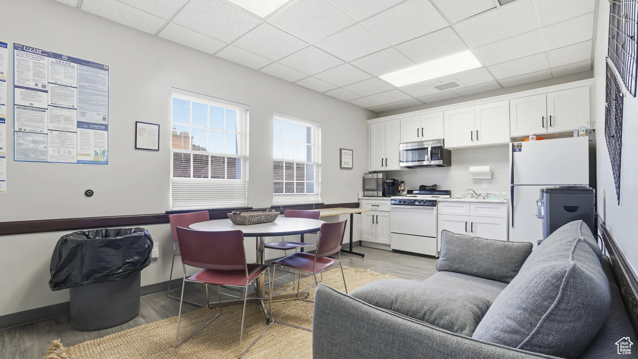 Kitchen featuring white appliances, white cabinets, a drop ceiling, and light countertops
