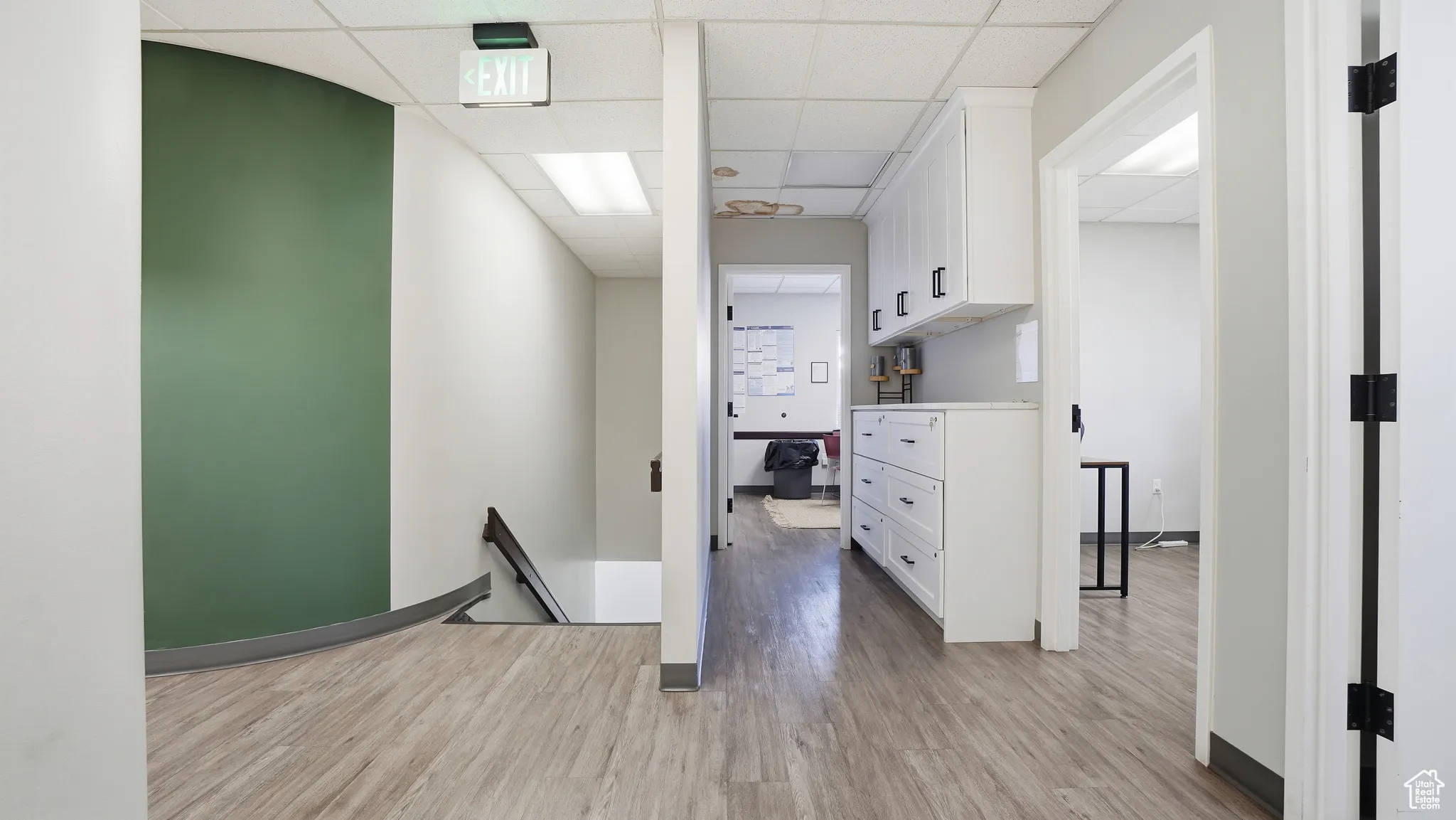 Corridor featuring an upstairs landing, light wood-style floors, and a paneled ceiling
