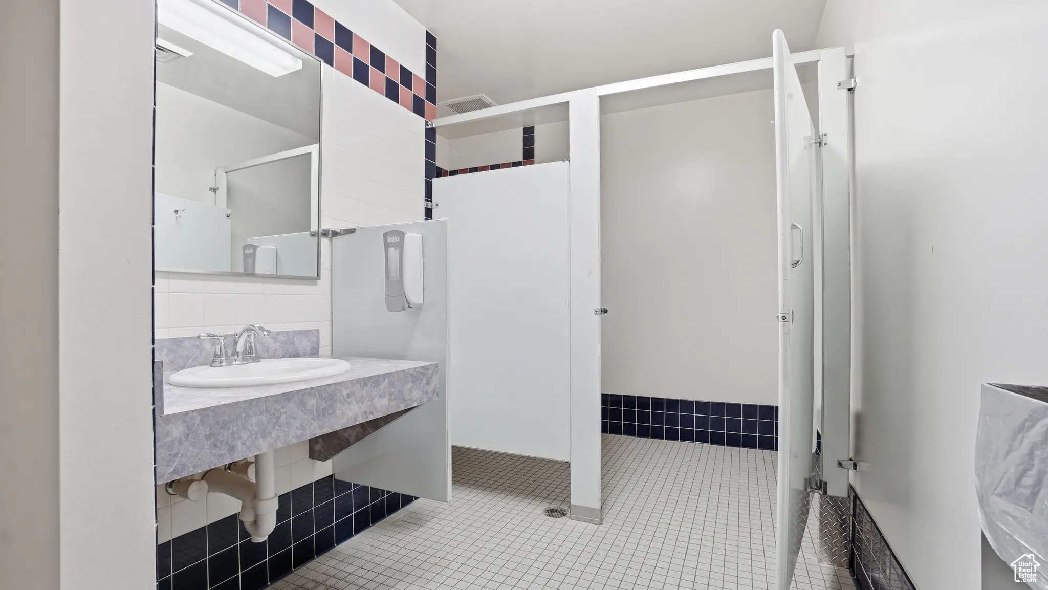 Bathroom with light tile patterned flooring, a shower stall, and tasteful backsplash