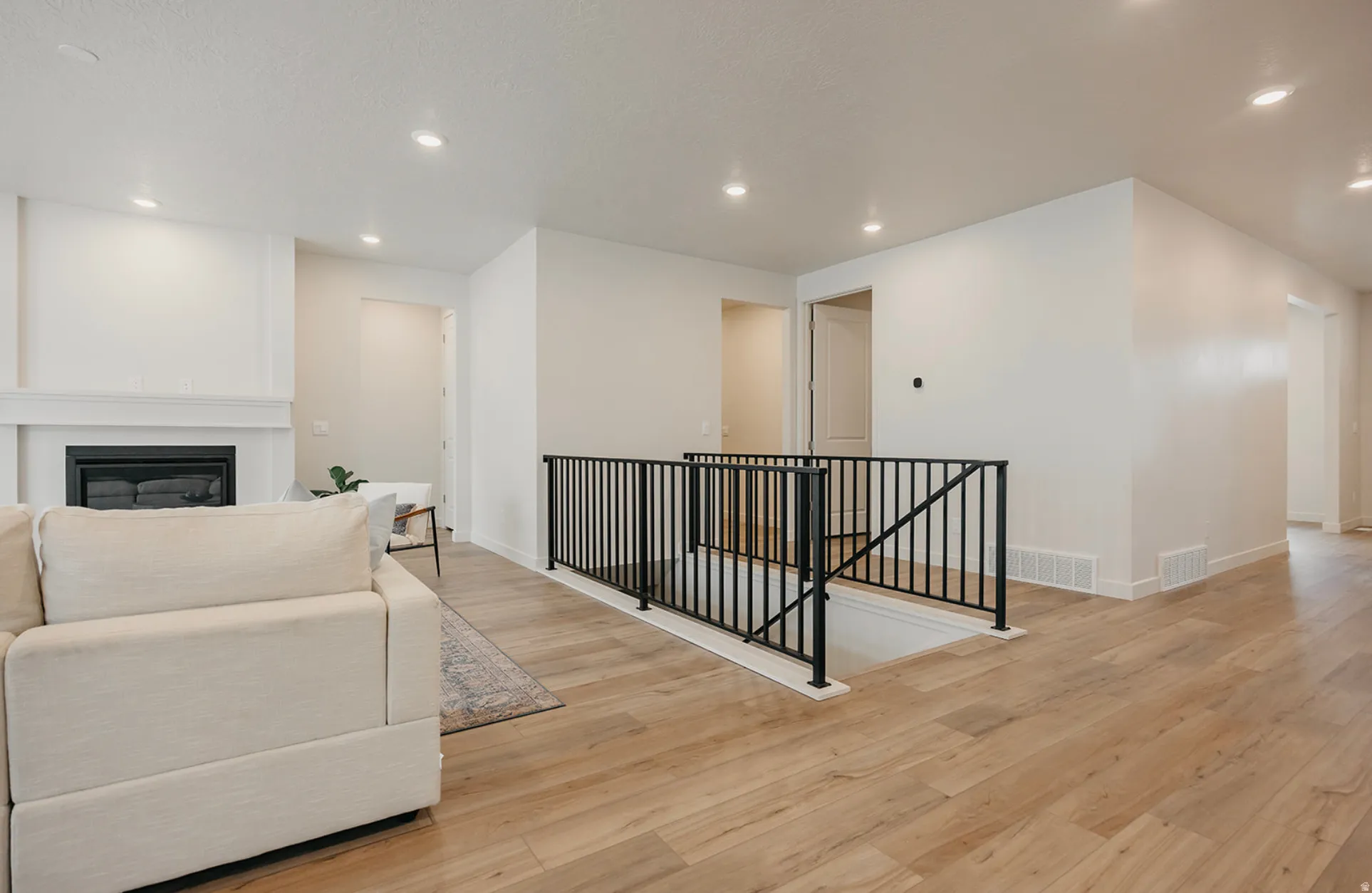 Open concept living area featuring wood-finish flooring and a contemporary black metal railing