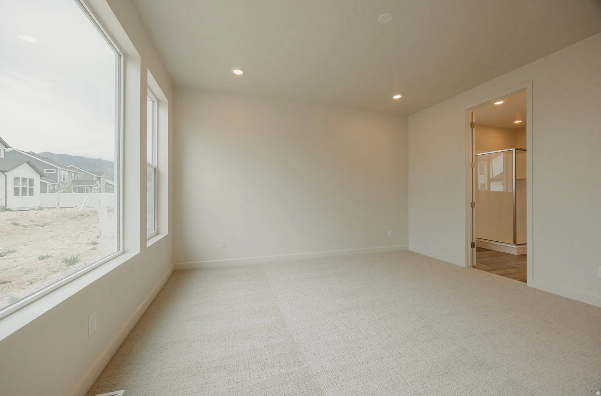 Spacious interior room featuring light-toned carpeting and recessed ceiling lighting