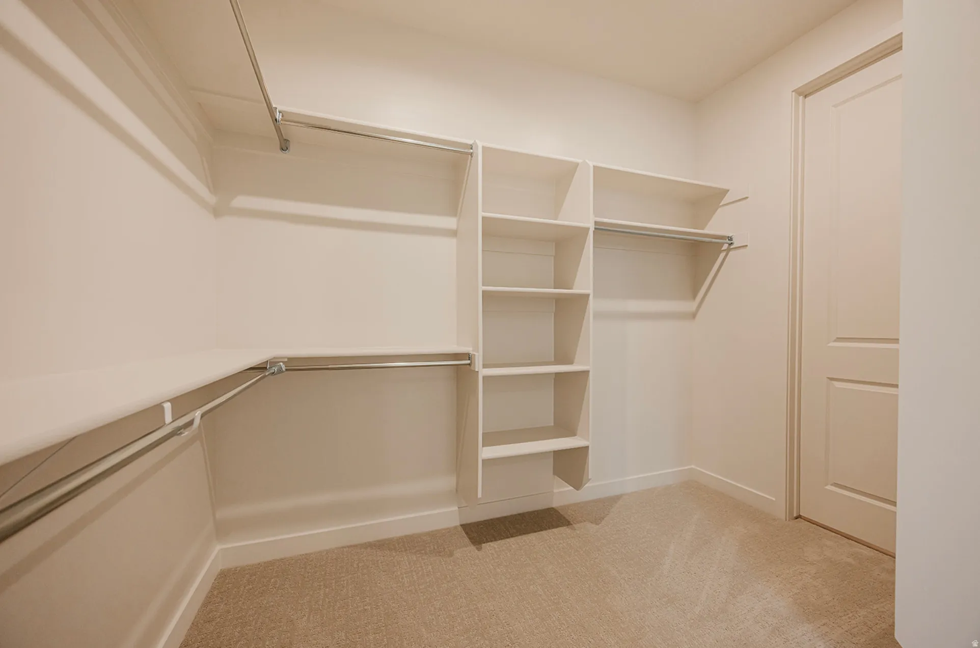 Walk-in closet featuring built-in shelving, multiple hanging rods, and neutral-toned carpeting