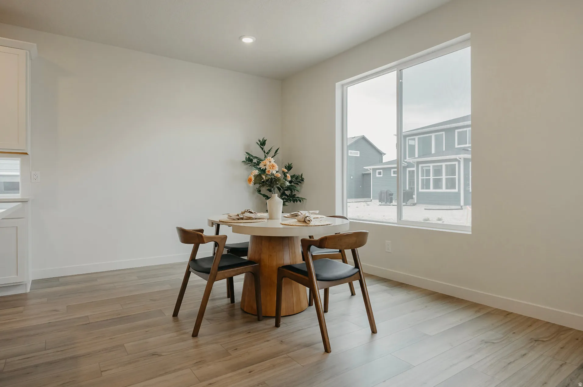 Spacious dining area featuring a large picture window, recessed lighting, wood-finish flooring, and white baseboards