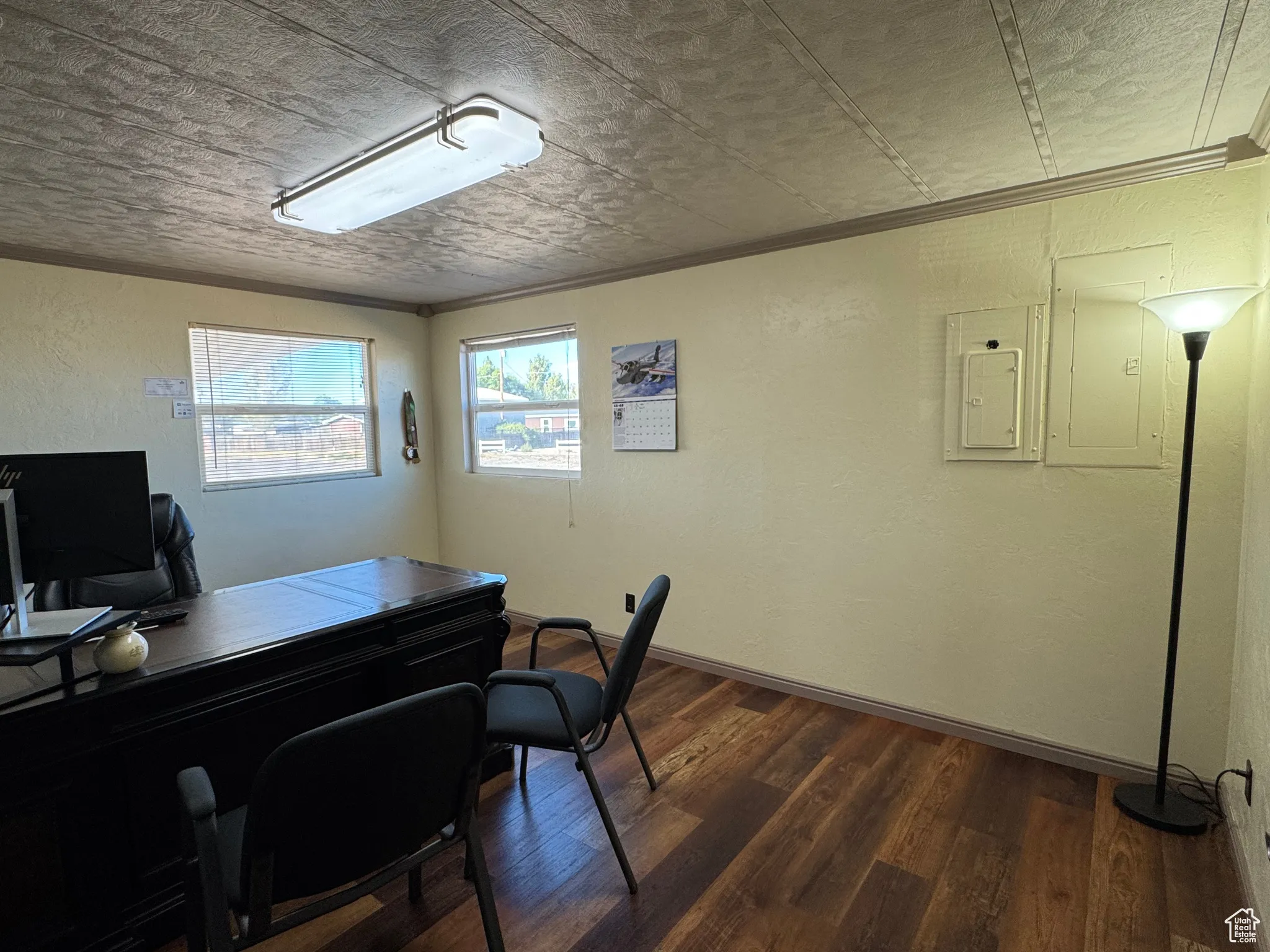Office with a textured wall, dark wood-style floors, electric panel, crown molding, and a textured ceiling