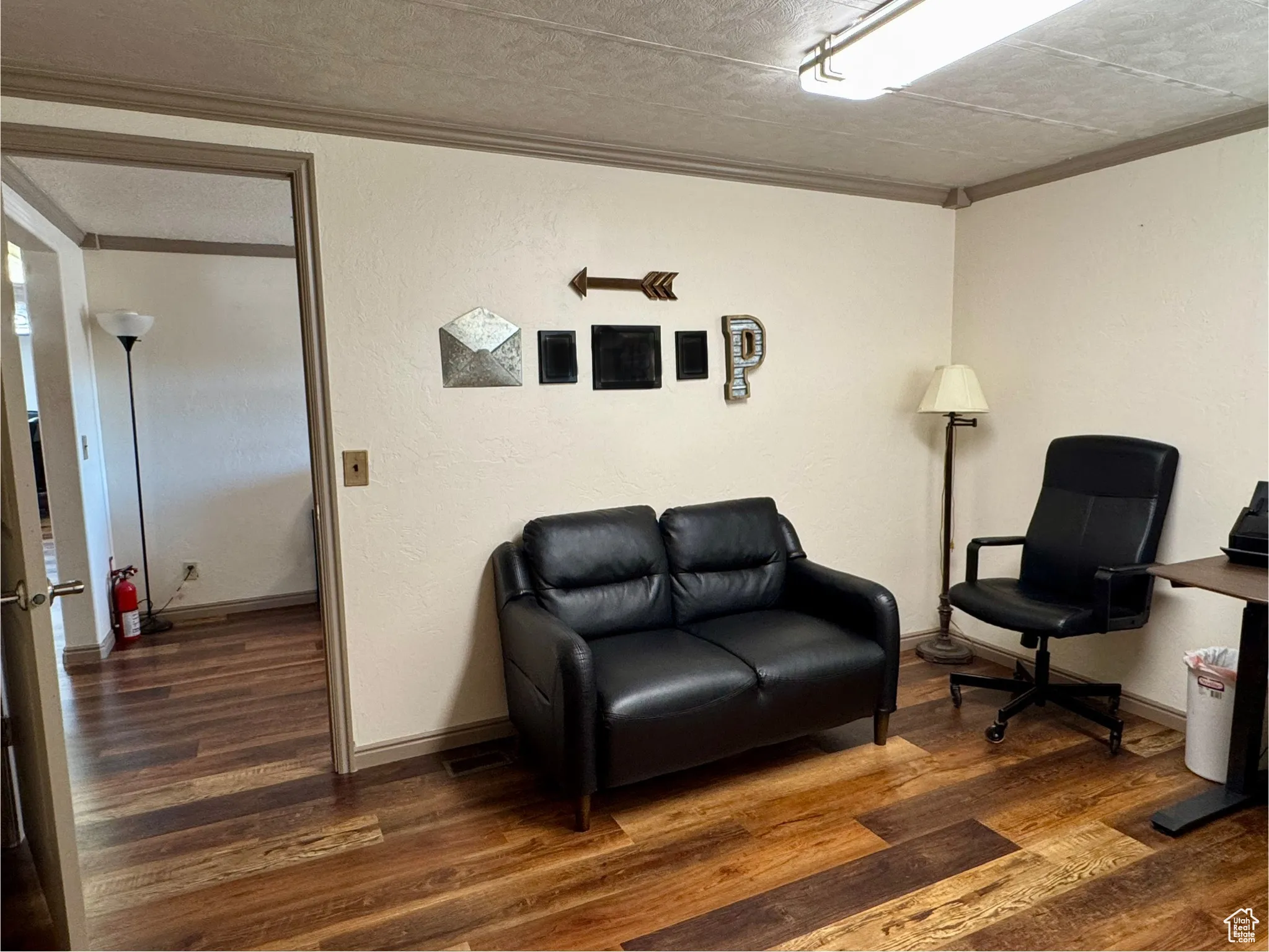 Sitting room featuring dark wood-style flooring, a textured wall, crown molding, and a textured ceiling