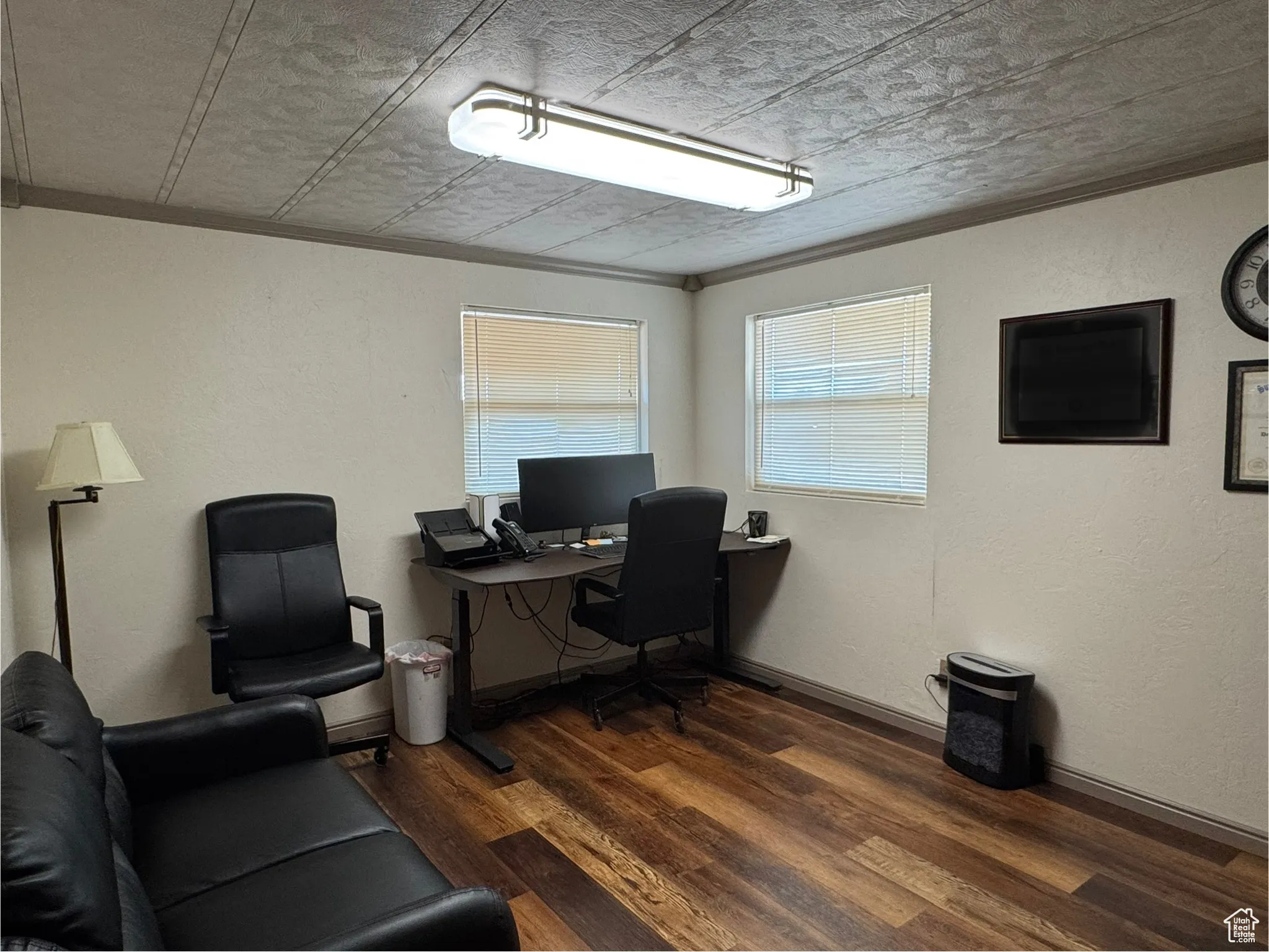 Home office featuring a textured wall, dark wood-style floors, and crown molding
