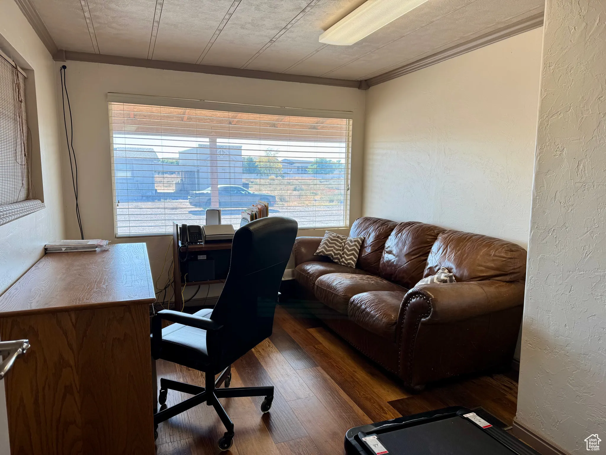 Office featuring a textured wall, dark wood-type flooring, and ornamental molding
