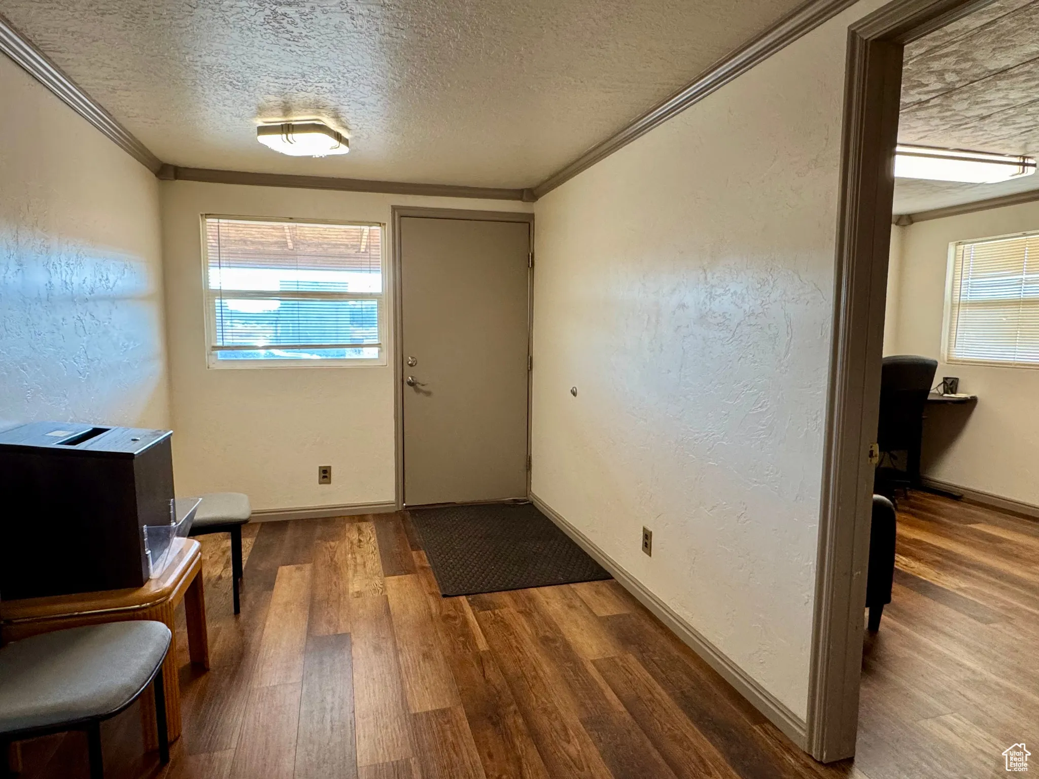 Entrance foyer with a textured wall, wood finished floors, ornamental molding, a textured ceiling, and healthy amount of natural light